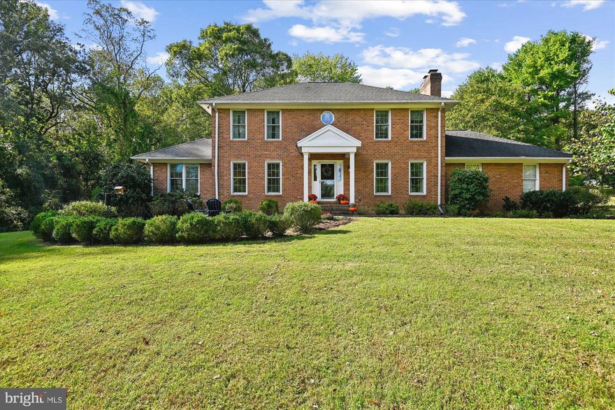 Welcome to 2034 Huntwood Drive, a beautifully updated brick-front Colonial set on 1.06 acres of grassy lawn, bordered by mature woods for peace and privacy. This spacious home blends timeless curb appeal with thoughtful modern upgrades inside and out. The heart of the home is the gourmet kitchen, fully renovated in 2023 by Solstice, featuring custom cabinetry, designer finishes, and a built-in coffee bar—perfect for mornings at home or entertaining guests. A dining room, currently used as a music room, has plenty of space for large gatherings. A den/office/playroom with French doors is a bright and flexible space.  The main level offers even more comfort and flexibility with a bedroom and full guest bath, ideal for visitors or multi-generational living. Upstairs, you’ll find three generous bedrooms and two full bathrooms, including the serene owner’s suite. This retreat boasts a spa-like travertine shower, soaking tub, and a California Closets walk-in closet (2020) designed for maximum organization. Step outside and enjoy the home’s screened porch overlooking the private backyard, as well as a paver patio with room for a fire pit—a perfect setting for outdoor dining, gatherings, or quiet evenings under the stars. The unfinished basement means you'll have plenty of storage space, or a clean slate to design your new living space and add quick equity to the home. Recent updates ensure peace of mind and efficiency: Hardie siding (2022), replacement windows, well pump, and a water treatment system with reverse osmosis. This exceptional property not only offers space and privacy, but also the benefit of being located in the new Crofton High School district with easy access to Annapolis, Ft. Meade, Washington, D.C., and Baltimore.