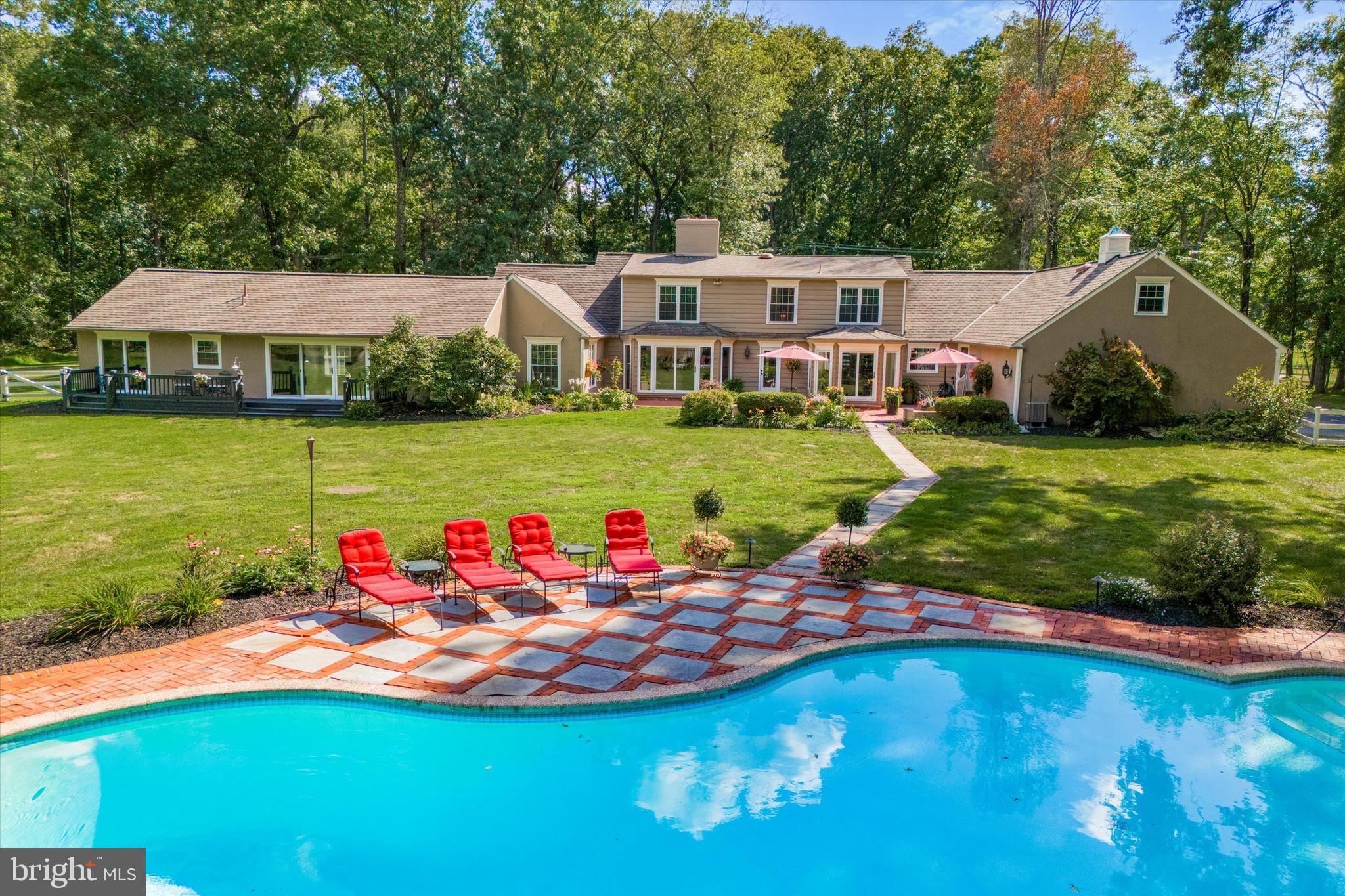 Welcome to your dream home, a stunning mini estate featuring a 2-story expanded cape cod nestled on six picturesque wooded acres, offering the perfect blend of classic elegance and modern convenience. As you approach the property you are greeted by two separate gated main entrances leading to circular driveway, ensuring both privacy and grandeur.
Entering through the main entrance, the foyer welcomes you with formal marble flooring and a newly renovated wet bar, perfect for entertaining. The large dining room is ideal for hosting dinner parties and family gatherings, while the expansive living room features a cozy fireplace. Moving through the foyer, you enter the spacious family room which boasts heated terra cotta flooring and another fireplace, providing a comfortable space for relaxation and entertainment.
The double kitchen is a chefs dream equipped with modern appliances, ample counter space and custom cabinetry. The kitchen includes a charming breakfast nook surrounded by windows, offering a perfect spot for morning coffee while overlooking the beautiful backyard. Additionally a butler’s pantry enhances the kitchens functionality and storage. Marble tile flooring in the kitchen adds durability and charm. The entire back of the house is adorned with windows and glass doors, providing stunning views of the expansive outdoor space.
The main house features five generously sized bedrooms with hardwood floors. On the first floor the luxurious master suite is a true retreat, complete with a newly renovated expansive master bath featuring heated floors, walk-in shower and elegant fixtures. Another bedroom on the first floor also boasts its own full bath, making it perfect for guests. A convenient half bath is located downstairs for visitors.
Ascending to the second floor you will find three additional bedrooms, each designed for comfort and privacy. An upstairs bonus room offers versatile space that can be used as an office, playroom or media room. The full bath upstairs is meticulously designed, combining functionality with high-end touches, insuring comfort for all occupants.
Adjacent to the main house the separate in-law suite offers a private living space ideal for guests or extended family. This suite features its own living room, dining room, kitchen and laundry facilities. Two bedrooms and a full bath provide ample space, while the back porch offers a tranquil spot to enjoy the surrounding nature.
Outside the expansive property truly shines. The large back and side lawns are perfect for outdoor activities, gardening or simply enjoying the great outdoors. A picturesque 1 acre lily pond with an island adds a touch of tranquility and natural beauty, creating a serene oasis where you can unwind. The large back brick terrace of the main house features a walkway leading to a heated swimming pool, perfect for year-round fun and relaxation.
The prime location allows you to enjoy the charm of nearby Peddlers Village and Carversville. With close proximity to the vibrant towns of Doylestown and New Hope, you’ll have easy access to a variety of shopping, dining and cultural experiences.
This charming home is more than a house. It is a sanctuary that offers a perfect blend of classic elegance, modern comfort, privacy and natural beauty.