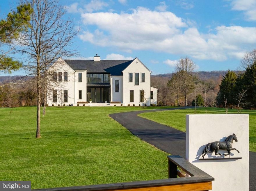 Set on a serene 10-acre parcel which is part of a small private community with no HOA, that has a majestic Blue Ridge mountain and pond views. This newly built estate offers a little over 8000 square feet of refined living space and a seamless blend of European modern elegance and timeless craftsmanship. A welcoming pier entrance and limestone walkway lead to a stucco façade accented by large glass gallery wall units and a 10’ tall glass door courtesy of Marvin Ultimate and Elevate windows.

Inside, soaring ceilings—including a 15-foot vaulted kitchen eating area, multiple archway openings, 10-foot on the main level. The heart of the home is an expansive chef’s kitchen featuring custom cabinetry, a white-oak island, Taj Mahal quartzite counters and backsplash, and a walk-in pantry with a custom white oak and glass entrance door, cabinets with quartzite countertops, full freezer, and abundant storage. Exposed white oak beams crown the kitchen and dining area, while a boxed white oak ceiling warms the family room. The centerpiece of the family room is a propane fireplace with a limestone surround profile and exotic quartzite mantel and hearth, which adds to the ambiance. The mudroom off the garage features a tiled dog wash for furry feet or the human kind. One will also find on the main level a beautiful arched topped wet bar appointed with limestone backsplash and custom metal frame with glass shelving. Main staircase consists of white oak treads and risers with a hand welded metal railing.

The thoughtful layout includes five bedrooms plus a lower-level bonus room, five full baths, and a powder room. The upper-level primary suite boasts 10-foot ceilings, a spa bath with a custom vanity and mirror surround, and two walk-in closets with bespoke built-ins. Additional highlights include a main-level full bath, upper-level laundry, custom bookcases, and an office/guest room with an accent wall and custom-made metal/glass-panel doors and transoms.

The finished lower level features a wet bar with custom metal wine racks and dishwasher, a second beverage center, fireplace, large exercise room, office area with egress window, and full shower bath, and a 6’ sliding door leading to the rear backyard.

Outdoor living shines with vaulted back porch supported by steel columns and braces for an upgraded design, beautiful chandelier, all set off by limestone pavers, perfect for year-round enjoyment.

Practical luxury abounds: 5-zone HVAC with humidifier, spray-foam insulation, a 5-bedroom septic and well system, three-car garage with EV charger, mudroom with cubbies and built-in storage cabinet. Professional landscaping combines sod, seeded lawn, and new trees for a polished yet natural setting.

This estate delivers the rare combination of modern design, artisan details, and pastoral privacy—an extraordinary retreat only minutes from everyday conveniences. Easy access to Gainesville, Manassas, Leesburg, international airports, and Bull Run Golf Club.