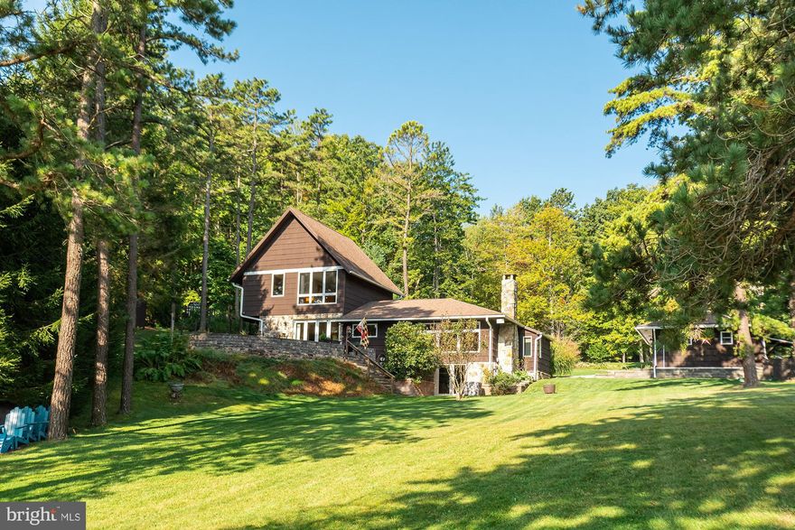 Old Deep Creek - only better! Original cabin on prime lakefront has been carefully expanded and renovated to today's highest standards. Large windows make the most of the spectacular view, one mile across the lake to Little Snaggy Mountain. A large brick and stone patio offers an excellent, private vantage point over the level lawn to the lake and a Type A dock, which the sun shines all all day long. The dining area is separated from the patio by an Anderson glass accordion door with retracting screen, so you can enjoy the benefits of outdoor dining without the bugs and the rain! Inside, the living room with its original native stone fireplace, is a cozy respite with a relaxing view. There are four bedrooms and three full bathrooms (a fourth is roughed in) plus a powder room on the main floor. The glass front door and entry way offer an immediate view to the lake and feature built-in storage and a bench. The central lake location gives quick access to parks, restaurants, and shops. This gem on the lake is the perfect place to gather family and friends and enjoy the beauty of Deep Creek.