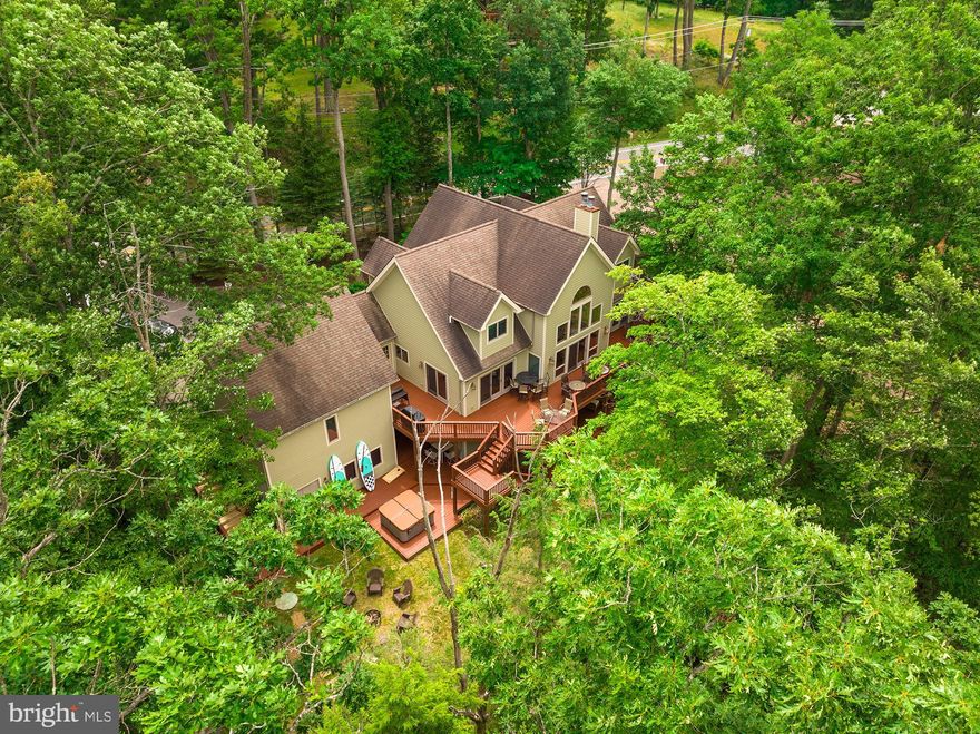 Stunning lakefront home offering 61' of frontage on Deep Creek Lake. This contemporary offers six bedrooms (five of which are en suites), an open floorplan, hardwood floors, two stone propane fireplaces, and a large loft area. The cathedral ceilings and abundance of large windows bring the beauty of the outside in during any season. You will be delighted with gorgeous lake and mountain views from almost every room. The outside features are also impressive, offering multiple decks, 2 hot tubs, an attached garage, and two storage rooms. This home is truly ideal for entertaining family and friends. The location is just one more plus - minutes to restaurants, grocery stores, DCL State Park, and Wisp Ski Resort. Established rental "Laurel Cove", grossing  $150,000 over the last 4 years. Approved to sleep 25, with parking for 7 cars.