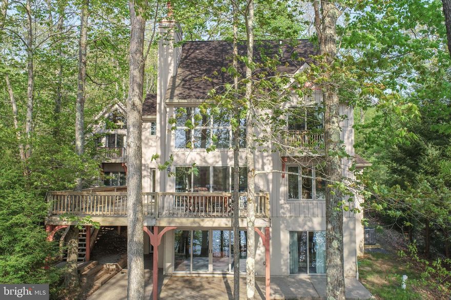 Unique offering of a custom designed French Chateau bringing all the best to lakefront living with a distinctive style, dramatic rock formations, protected cove location, and private Type A dock.  This one-of-a kind resort retreat spans 115' across one of the most beautiful shorelines anywhere on Deep Creek Lake.  Created by architect Phill Silkey for Gosnell Builders to take advantage of the magnificent boulder strewn lot, this lake home exemplifies what a lakefront home should be: Close to the shore with stunning lake views, architecturally designed with gathering space inside and out, low maintenance inside and outside so your time is spent enjoying your family and guests.  The main level highlights post and beam construction and is completely open allowing lake views from every corner.  A stacked-stone fireplace climbs to the top of the partially vaulted Great Room space set against a wall of glass allowing natural light to fill the area.  The vaulted Primary Bedroom Suite with sliding doors and lakeside balcony occupies the second level and features a separate sitting room with a direct lake view perfect for working at home.  The lower-level features three Bedrooms, all with lake views, and the warmth of a second stacked-stone fireplace in the lakeside Family Room.  The Carriage House above the garage offers the same lake views, open-beam construction, vaulted wood ceiling, hardwood floors, full bathroom, and a separate bunk room making it perfect for a family of four.  This single owner home is offered fully furnished and has never been rented so just enjoy coffee in the morning sun and let your cares float away.  Don’t miss this one, it's in a class by itself.