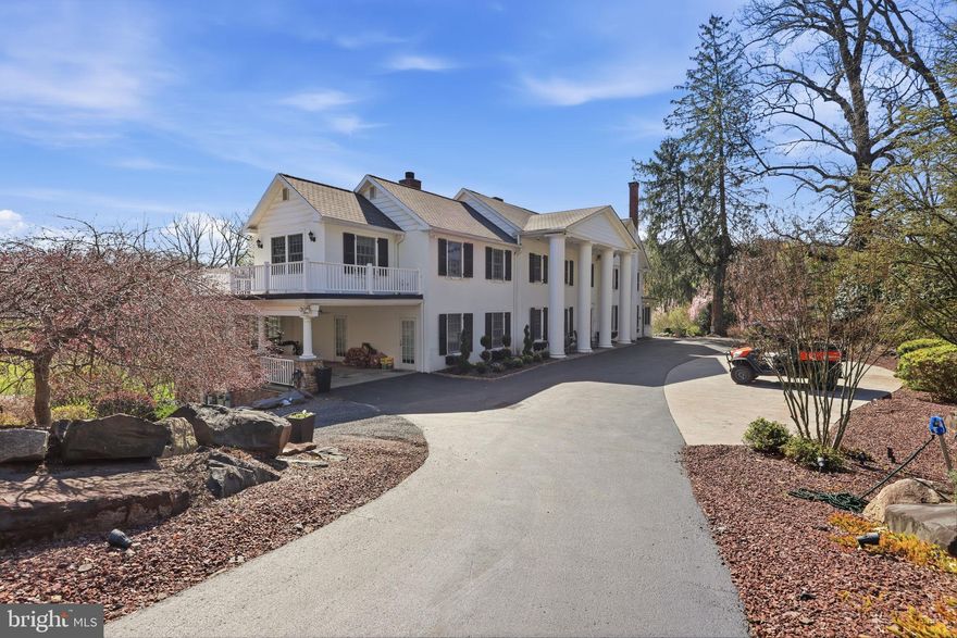 Glenloch Manor is the rare property that delivers both architectural presence and true compound living. Positioned behind wrought-iron gates and approached by a long, multi-car drive, this 11-acre estate unfolds around a picturesque heart-shaped pond with bridges, fountain, gardens, play areas, and curated outdoor living spaces. Privacy is absolute. The lifestyle is expansive. The Main Residence - A stately Greek Revival façade with grand columns and a classic shingle roof sets the tone. Inside, historic character meets modern luxury across thoughtfully renovated spaces designed for both large-scale entertaining and comfortable daily living. The main level welcomes you with a stone-tiled foyer and flows into elegant formal rooms, multiple wood-burning fireplaces, a refined dining room, and a richly appointed family room with custom bar. The gourmet kitchen is a true centerpiece, featuring marble countertops, white cabinetry, Wolf six-burner range, wine refrigeration, expansive breakfast area, and seamless connection to a prep/bar kitchen and sunroom overlooking the grounds. A game room, office/sitting room, and covered patio/carport extend the entertaining footprint. The lower level offers exceptional versatility with a secondary kitchen, full bath, finished recreation area with wood stove, gym, sauna, wine cellar, additional laundry, and extensive storage/mechanical space. A whole-house generator, hot water heat, well system, and upgraded infrastructure provide peace of mind. Upstairs, the primary suite is its own private retreat, complete with gas fireplace, expansive sitting room, private office with balcony access, massive custom dressing room with integrated laundry, and a spa-inspired bath. Additional bedrooms include princess suites and cedar-lined storage, each designed with comfort and privacy in mind. A top-level loft bedroom and sitting area add yet another flexible living space. The Carriage House - The oversized two-car carriage house with gas HVAC and hot water offers fully independent living. Hardwood floors, open living spaces with wood-burning fireplace and balcony, white kitchen with quartz counters and stainless appliances, multiple bedrooms including a primary suite, full baths, dedicated laundry, and a third-floor loft with mini-split climate control create an ideal guest residence, multigenerational suite, or private office retreat. The Luxury Barn House - The barn is nothing short of spectacular. With a metal roof, open-concept design, concrete floors, reclaimed finishes, full kitchen and bar with granite counters and antique oak cabinetry, large pantry, wood-burning stone fireplace, covered patio, and climate control, it functions as a next-level entertainment venue. Upstairs, a dramatic open gathering space, powder room, and dedicated cigar lounge elevate the experience even further. The Retro-Inspired Pool House (pics coming soon) - Positioned for effortless summer living, the pool house features slate flooring, sliders to outdoor entertaining areas, full kitchen with electric cooking, full bath, upper-level space, and mini-split comfort. A hot tub, aerated pond, and lush grounds create a resort-style atmosphere rarely found in private estates. The Grounds & Infrastructure - The property is as functional as it is beautiful, offering sprinkler system, centrifugal pump, solar array for efficiency, multiple car parking areas, covered patios, and expansive driveways. The pond, gardens, bridges, and mature landscaping create a setting that feels both curated and natural. Located just minutes from New Hope, Doylestown, and Newtown, Glenloch Manor delivers complete seclusion without sacrificing convenience. This is a legacy property designed for those who want space to gather, space to retreat, and the flexibility to live expansively. A true family compound where every structure serves a purpose and every detail supports a lifestyle few properties can offer.