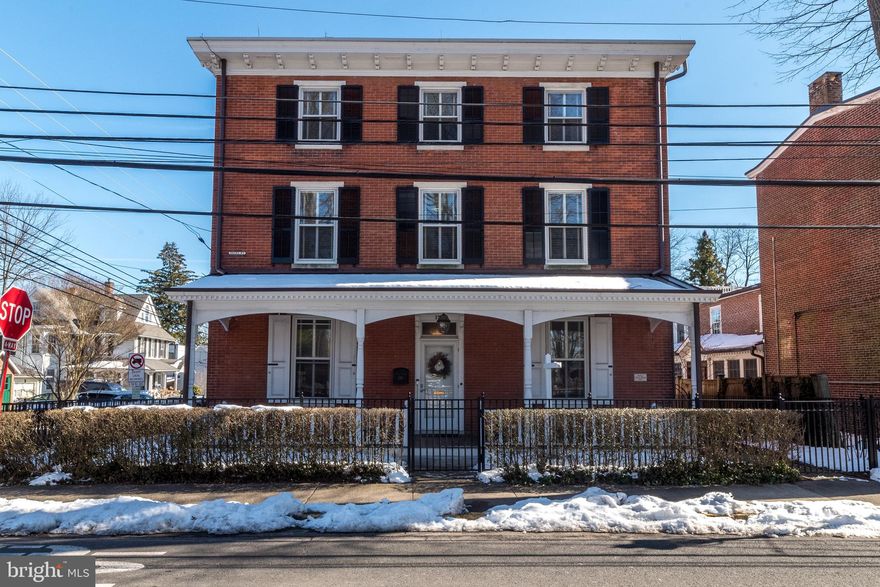 This stately home is situated perfectly on a spacious corner lot in the center of Doylestown Borough. The brick exterior lends itself to a timeless era while the interior updates offer modern sophistication. Dating back to 1867 it is a mix of historic features with an updated flare. The impressive front porch offers a shady spot to relax. This beautiful home offers 3908 feet of living space on three floors. The first floor boasts ten-foot ceilings throughout with mostly hardwood. The gorgeous molding and deep window wells add to the ambiance. The floor plan lends itself to versatility depending on your needs. A beautiful gas-burning fireplace can be found in the spacious family room with folding French doors allowing the light to enter brightly. You will love the custom built-in shelving for storage and display.  In the rear of the first floor, you will find a newer addition that offers a kitchen for a chef with a cathedral ceiling, gorgeous cabinetry, a six-burner Wolfe commercial range including double ovens, and a Sub-Zero refrigerator. In addition, there is a large island with a built-in microwave, warming drawer, and under-counter beverage cooler.  Exposed brick, granite countertops, and recessed lighting complete this modern space. The sunny breakfast area encompassed with windows and a full view atrium door leads to the rear yard brick patio where you will find the perfect spot for outdoor living and entertainment. A brick walkway leads to the oversized two-car garage with an upper storage area. The second floor offers impressive nine-foot ceilings, a spacious master bedroom with a large custom walk-in closet, a master bath, and a private water closet. A second bedroom, sitting area, and full bath can be found on this floor. The third floor offers a bedroom with an office/sitting room, a nice-sized library, and two additional bedrooms that lead to a shared hall bath. Need more space? The unfinished basement is readily available for a gym, game room, wine cellar, or whatever you desire. An elevator is the perfect surprise, making it easy to access all three floors with the touch of a button. This beautifully finished historic home offers all the conveniences you need with accessibility to some of the best dining, shops, and cultural attractions just a short walk away. Don’t wait to start living your best life.