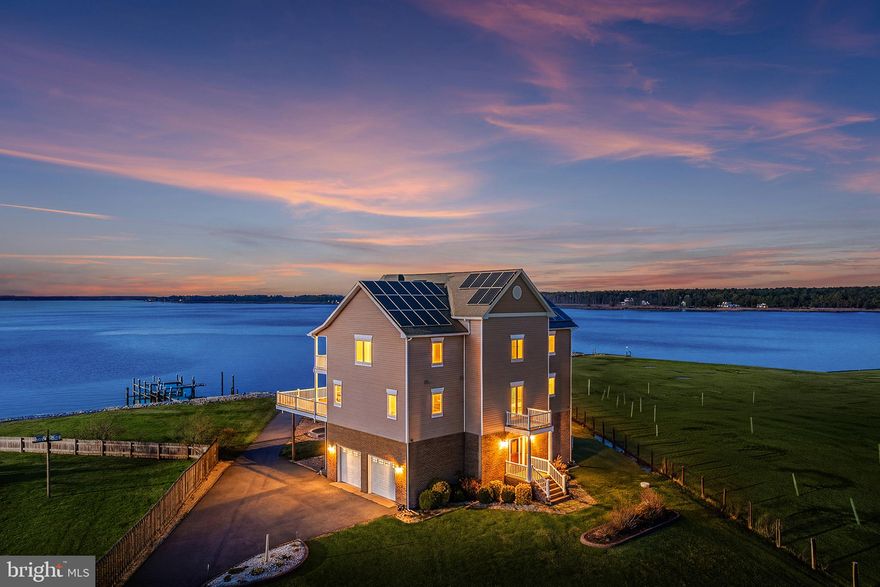 End each day with sweeping sunsets over Madison Bay from this exceptional waterfront compound offering 268 feet of protected, rip-rapped shoreline and 1.12 acres of privacy, ideally positioned with a coveted east-west orientation. A private pier equipped with a boat lift and personal watercraft lift enhances the property’s appeal, delivering immediate access to the water and an effortless boating lifestyle. Designed by renowned architect Burhsar Pathare, the impeccably crafted residence spans over 5,000 square feet across three finished levels, featuring 4 bedrooms and 4.5 baths, all thoughtfully positioned to capture unobstructed water views. Beautiful flooring flows throughout, complementing clean architectural lines and high-end finishes. The entry level welcomes you with a large living space highlighted by high ceilings and an abundance of windows that frame stunning water views. A beautiful, full-service bar—complete with sink, dishwasher, and high-end finishes—creates the perfect setting for entertaining. This level also features a spacious laundry and utility area along with a convenient half bath, and provides direct access to the backyard and waterfront setting for seamless indoor-outdoor living. Take the stairs or the elevator to access the upper levels of the home. The main level is truly striking, showcasing soaring 40-foot ceilings and a dramatic wall of glass capturing panoramic bay views. The open-concept design seamlessly integrates the kitchen, dining, and living areas, anchored by a stone fireplace. The gourmet kitchen features a spacious eat-in area and opens to a full-length wraparound deck overlooking the water—ideal for gatherings of any size. The main-level primary suite offers private deck access and a spa-like bath, with an additional full bath also located on this level. Upstairs, a loft overlooks the main living space, along with three generously sized bedrooms, including two ensuite bedrooms with private baths—each bedroom also features its own private deck overlooking the water, offering a peaceful retreat with breathtaking views. The third secondary bedroom features the added convenience of direct elevator access within the room itself. Outdoor living is equally impressive with multiple decking areas and a beautifully designed paver patio featuring a fire pit and sitting walls—all oriented to take full advantage of the waterfront setting. The property is fully fenced, enhancing both privacy and functionality.  A gated entrance with electronic access further enhances privacy and security, while an oversized two-car attached garage provides ample convenience and storage. The property is serviced by public sewer and a private well.  The residence is offered as a truly turnkey opportunity, conveying with the majority of its high-quality furnishings for an effortless, move-in-ready experience (select artwork and personal items excluded). The adjoining property at 1250 Old Madison Road is also available for purchase (MDDO2012114), featuring a charming 2-bedroom, 2-bath cottage with additional living space and expansive water views—ideal as a guest house or income-producing rental. An exceptional opportunity to fully embrace the waterfront lifestyle—where every day feels like a retreat and lasting memories are made. Mortgage savings may be available for buyers of this listing.