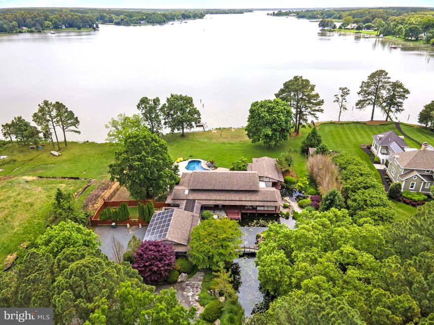 Welcome to this serene oasis nestled on the coveted Miles River, where tranquility meets luxury in this Japanese-inspired waterfront property. The meticulously crafted home has been curated to offer the ultimate in comfort, style, and refined elegance. The exterior of the home is a masterpiece of design, featuring lush gardens with native plants and flowers, trickling fountains, attractive foot bridges, and a Koi pond, creating a sense of peace, serenity, and privacy. A swimming pool, private pier with 3'+/- MLW, designated barbecue area, extensive patio, storage shed, and 2-car attached garage complete the exterior amenities. Inside, admire gleaming hardwood floors, custom cabinetry, and designer finishes throughout. The gourmet kitchen, featuring upgraded appliances, provides ample space for preparing culinary creations. Entertain guests in the luxurious living room, featuring a wet bar with wine storage, or enjoy a formal meal in the dining room, while enjoying views of the river, pool, and gorgeous grounds. The primary suite is conveniently located on the main level, offering a sumptuous ensuite bath with glass-enclosed shower and soaking tub, walk-in closet, and private waterside deck. Two additional bedrooms upstairs, each with their own private balcony and ensuite bath, and a bonus room, offer plenty of space for guests and storage.