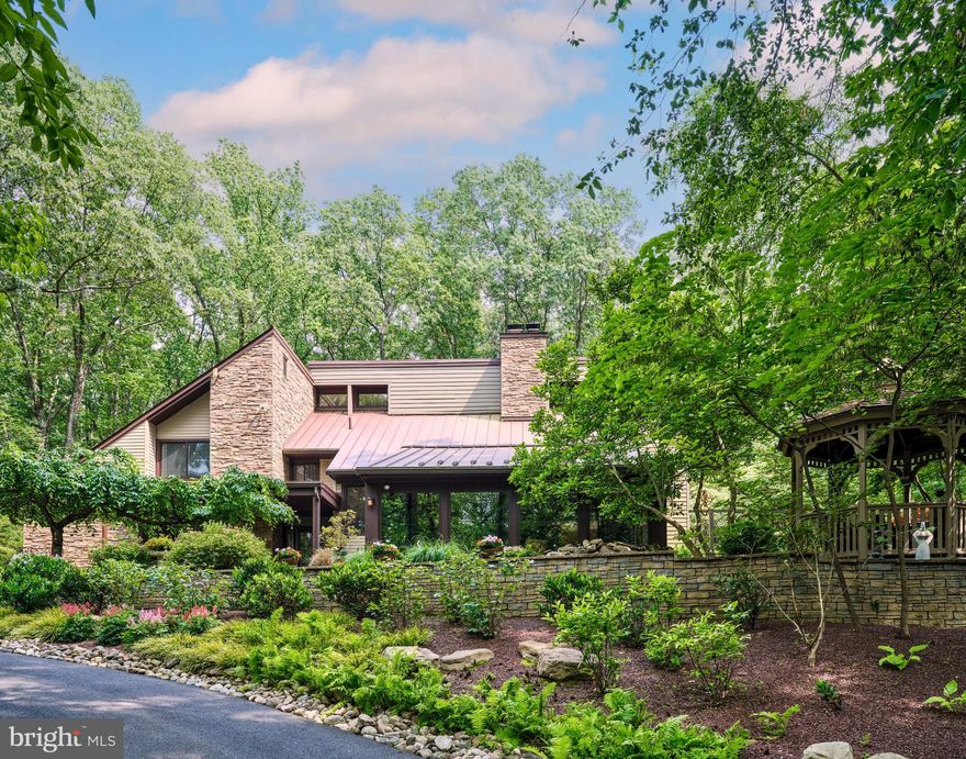 Embrace the joy of discovering "Paradise Found," a contemporary oasis nestled amidst nearly five private acres of enchantment, serenity, and natural splendor. A meandering driveway, bordered by stone terraces, mature gardens, meditation trails, and a richly populated koi pond, leads you to the hidden jewel of Ely Road in the charming town of New Hope, Pennsylvania.  As you step inside, the main floor offers a well-lit office space and an awe-inspiring two-story great room, featuring mirroring custom built book shelves that stretch from floor to ceiling. Adding a touch of rustic charm is a stone-finished wood-burning fireplace and a grand window display, allowing you to soak in the beauty of the gardens that encapsulate the property. The kitchen, both welcoming and functional, boasts a central island complete with a cooktop, a wall oven & warming drawer, a custom-made workstation, and a glass-walled sunroom offering stunning views of the pool haven. The journey upstairs brings you to the sumptuous primary suite, complete with a secluded deck off the bedroom, a luxurious bathroom w/ double vanity and glass shower, and a large walk-in closet with a private deck of its own. The second level also offers two additional, generously sized bedrooms, each adorned with skylights and equipped with their own bathrooms for ultimate convenience.  Adding to the exclusivity of the property is a custom-built wine cellar, showcasing an impressive wall of wine bottles and a full bar.  The backyard is a spectacle of its own with lush flowers and stone walls encircling the heated, saltwater pool with a cascading hot tub. Spend warm summer evenings around the outdoor fire pit, basking in the glow of an outdoor oasis illuminated by extensive landscape lighting. A freestanding garage, roomy enough for three cars, offers additional parking while providing a pristine work area for your tools and toys. This impeccably kept retreat is situated minutes away from the center of town, nestled within the prestigious New Hope-Solebury School District, and is strategically positioned nearby all primary commuter routes. If you've been on a quest for your next chapter, the one unique story that not only resonates with your head but also with your heart, then you have arrived at "Paradise Found". (Sellers are including ALL furniture and contents within home, both interior and exterior, with the sale.)