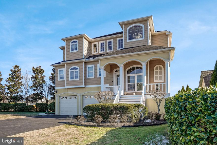 At the end of a serene canal, 8 Alton Point commands a breathtaking vantage point with expansive views up the waterway and across to the iconic Ocean City skyline. Bathed in prized southern exposure, this 4,000-square-foot custom residence captures both sunlight and scenery in a setting that feels private, picturesque, and distinctly coastal—all within the sought-after Terns Landing section of the vibrant Ocean Pines community.  Constructed by Heron Bay Builders using premium 2x6 framing and protected by 50-year shingles, the home exemplifies enduring quality and forward-thinking design. A high-performance geothermal HVAC system provides exceptional energy efficiency and impressive long-term savings, delivering year-round comfort with environmentally conscious performance. Every structural and mechanical element reflects a commitment to durability, sustainability, and superior craftsmanship.
Inside, exotic solid Angelim hardwood floors glow beneath tray ceilings and custom lighting. Archways, shadow box molding, and detailed carpentry create architectural depth and timeless appeal. Custom cabinetry throughout the home pairs beauty with function, while thoughtfully upgraded lighting enhances every space.  Designed to celebrate its waterfront location, the open-concept kitchen, dining, and living areas capture breathtaking views while offering seamless functionality. The chef’s kitchen boasts commercial-grade appliances, a gas cooktop, dual wall ovens, two Fisher & Paykel drawer dishwashers, custom cabinetry, and generous prep space, ideal for entertaining against a backdrop of shimmering water and city lights.
Three primary bedroom suites each provide private bathrooms, offering luxurious accommodations for residents and guests. One upper-level suite features a whirlpool tub, perfect for unwinding after a long day. A flexible entry-level bonus room  serves as a potential fourth bedroom, office, or creative space, and  a recently installed elevator ensures convenient access throughout the home.  Outdoor living defines the experience of this home. Enjoy coastal breezes from the screened porch, two balconies, and the rooftop deck. Host gatherings on the newly added rear patio, surrounded by beautiful, mature gardens, expanded irrigation, and improved drainage. An outdoor shower completes the waterfront lifestyle.  For boating enthusiasts, the upgraded pier, replaced bulkhead, and 4x20 dock with an 8,000 lb boat lift provide direct access to water adventures.  The oversized garage accommodates a 20-foot boat and trailer, enhanced by upgraded rubber flooring and expanded storage areas.  Extensive improvements since 2021—including the installation of an elevator, replaced bulkhead, LED lighting, upgraded bathroom fixtures, several new appliances, extensive exterior lighting, resealed driveway, and invisible fencing, just to name a few - underscore the meticulous care invested in this exceptional property. A true standout within the community, this remarkable residence was proudly featured on the Ocean City Art League’s Sand Castle Home Tour - an honor reserved for homes recognized for architectural excellence, distinctive design, and coastal elegance.  Ocean Pines offers more than a location; it offers a lifestyle. Set across 3,000 wooded acres with nine miles of waterfront, the community features five pools, two marinas, a yacht club, racquet facilities, and a Robert Trent Jones Sr.-designed championship golf course, along with access to a beachfront area and restaurant in Ocean City.  This is refined waterfront living—energy-efficient, architecturally celebrated, and crafted with intention—ready to inspire your next chapter.