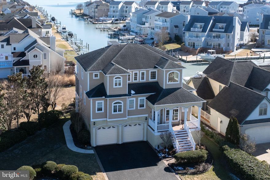 At the end of a serene canal within sought-after Terns Landing, 8 Alton Point commands a breathtaking vantage point with expansive views up the waterway and across to the iconic Ocean City skyline. Bathed in prized southern exposure, this 4,000-square-foot custom residence captures both sunlight and scenery in a setting that feels private, picturesque, and distinctly coastal—all within the vibrant Ocean Pines community.  Constructed by Heron Bay Builders using premium 2x6 framing and protected by 50-year shingles, the home exemplifies enduring quality. Inside, exotic solid Angelim hardwood floors glow beneath tray ceilings and custom lighting. Archways, shadow box molding, and detailed carpentry create architectural depth and timeless appeal.  Designed to celebrate its waterfront location, the open-concept kitchen, dining, and living areas capture panoramic views while offering seamless functionality. The chef’s kitchen boasts commercial-grade appliances, a gas cooktop, dual wall ovens, two Fisher & Paykel drawer dishwashers, custom cabinetry, and generous prep space—ideal for entertaining against a backdrop of shimmering water and city lights.  Three primary bedroom suites each provide private bathrooms, offering luxurious accommodations for residents and guests, all of which are easily accessible via elevator. One upper-level suite features a whirlpool tub, perfect for unwinding after a day on the bay. A flexible bonus room on the bottom level serves as a potential fourth bedroom, office, or creative space.   Outdoor living defines the experience. Enjoy coastal breezes from the screened porch, two balconies, and a rooftop deck. Host gatherings on the newly added patio, surrounded by mature gardens and an expanded irrigation system. An outdoor shower completes the waterfront lifestyle.  For boating enthusiasts, the upgraded pier, replaced bulkhead, and 4x20 dock with an 8,000 lb boat lift provide direct access to water adventures. The oversized garage accommodates a 20-foot boat and trailer, enhanced by upgraded flooring and expanded storage.  Extensive improvements since 2021—including LED lighting, custom draperies, updated fixtures, enhanced landscaping, resealed driveway, several new appliances, exterior lighting, and invisible fencing, just to name a few—underscore the meticulous care invested in this exceptional property.
Ocean Pines offers more than a location; it offers a lifestyle. Set across 3,000 wooded acres with nine miles of waterfront, the community features five pools, two marinas, a yacht club, racquet facilities, and a Robert Trent Jones Sr.-designed championship golf course, along with access to a beachfront restaurant in Ocean City.  This is refined waterfront living—crafted with intention, maintained with pride, and ready to inspire your next chapter.