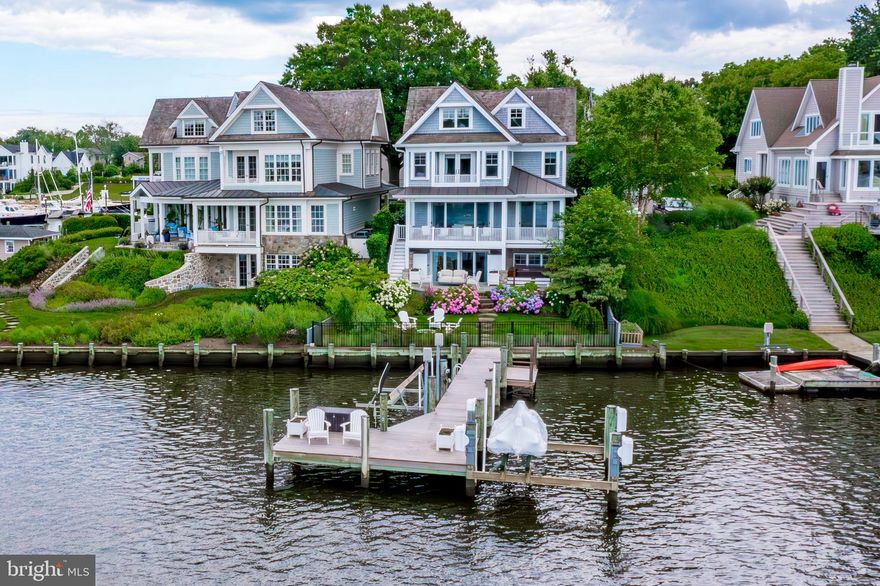 Discover a stunning Eastport waterfront home with great  views of the Annapolis City Skyline on desirable Spa Creek. This elegant residence features a deepwater private pier with 5-foot mean low water depth and two lifts. The home has approximately 4,000 finished square feet, offering three bedrooms and three and a half baths with flexible living spaces. Approaching the entrance, you'll be welcomed by hydrangeas and custom landscaping. The open concept first floor includes a dining area, a living room with a gas fireplace, and a striking kitchen with a large white marble cooking island and top-of-the-line appliances, all leading to a waterside deck that extends across the width of the house. The interior showcases 9-foot ceilings, 5-inch oak floors, coffered ceilings, built-in bookcases, and wainscoting, adding refined luxury. The second floor features a waterside primary suite with a spacious bath, a freestanding cast iron tub, and walk-in closets. Two additional bedrooms, a common sitting space, and a hall bath with water views are found on the third floor. The walk-out lower-level family room includes a gas fireplace, a mini kitchen with an icemaker, wine refrigerator, and sink, and opens to a flagstone patio with a hot tub and seating area, creating a fenced-in outdoor sanctuary. Detached one-car garage, built-in speakers, cedar shake siding, and a cedar roof.