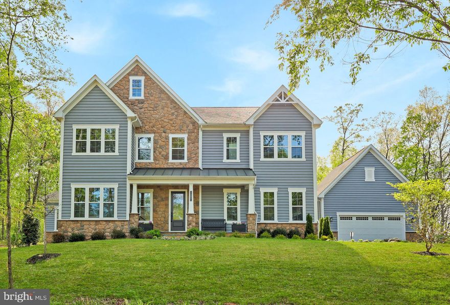 Don’t miss this exceptional and rare opportunity to own a masterfully crafted residence by D.R. Horton, America’s largest homebuilder, known for delivering quality construction, innovative design, and enduring value. Perfectly sited on a breathtaking 10-acre homesite backing to mature trees in Nokesville, this stunning Hampton II Colonial offers a remarkable blend of privacy, scenic beauty, and modern convenience in one of Northern Virginia’s most charming rural settings. With over $250,000 in thoughtful upgrades, this impressive residence spans approximately 8,200 square feet across three finished levels, featuring six spacious bedrooms, six and a half baths, and a four-car garage, all complemented by a welcoming front porch designed for everyday living. A grand two-story foyer creates a striking first impression and opens to an expansive floor plan filled with natural light and elegant finishes throughout. At the front of the home, a private formal office with French doors, oversized windows, and recessed lighting provides a quiet and polished workspace. The formal dining room showcases a tray ceiling, elegant chandelier, and walls of windows overlooking lush greenery, creating a sophisticated setting for both intimate meals and large gatherings. A conveniently located half bath completes the main level. The heart of the home is the expansive family room, highlighted by decorative ceiling beams, recessed lighting, and a gas fireplace with a modern mantel, creating a warm and inviting atmosphere. The adjoining gourmet kitchen is a chef’s dream, featuring quartz countertops, a stylish backsplash, and a high-end stainless steel appliance package including a 36-inch commercial gas range, 48-inch refrigerator, dishwasher, and combination microwave and wall oven. Upgraded soft-close cabinetry, stacked glass-front cabinets with puck lighting, and extensive built-in storage with pull-out drawers provide both beauty and functionality. The oversized island with sink and cabinetry on all sides serves as the perfect centerpiece for entertaining. The adjoining breakfast area includes additional cabinetry and a beverage bar, offering a cozy space for casual dining while overlooking the serene wooded backyard. Just beyond, a stunning solarium surrounded by windows provides endless flexibility, ideal for a greenhouse, home office, fitness room, or creative studio. The main level also features a mudroom entry from the garage with a built-in drop zone, lockers, and custom cabinetry for everyday organization. A private main-level bedroom suite offers excellent flexibility for guests or multigenerational living, complete with a full bath featuring a frameless glass shower, floor-to-ceiling tile, quartz vanity, and water closet. Upstairs, a beautifully upgraded staircase with modern oak railings leads to a refined bedroom level finished with luxury vinyl plank flooring throughout. The primary suite offers a tray ceiling, recessed lighting, and dual custom walk-in closets. The spa-inspired bath features dual frameless glass showers, floor-to-ceiling tile, a freestanding soaking tub, expansive quartz vanities with soft-close cabinetry, and a private water closet. Three additional bedrooms, each with walk-in closets and private full baths, provide comfort and privacy. The walk-up lower level is equally impressive, featuring a spacious recreation room, a versatile bonus area ideal for a media room or gym, and a sixth bedroom with a full bath and large walk-in closet. A generous storage area provides ample space for seasonal items and household needs. Meticulously maintained and richly upgraded, this remarkable home offers timeless elegance, modern comfort, and an exceptional lifestyle opportunity in Nokesville. Enjoy nearby attractions such as Burnside Farms and Wineries, along with convenient access to shopping, dining, and entertainment at Virginia Gateway and major commuter routes including Route 66 and Route 29.