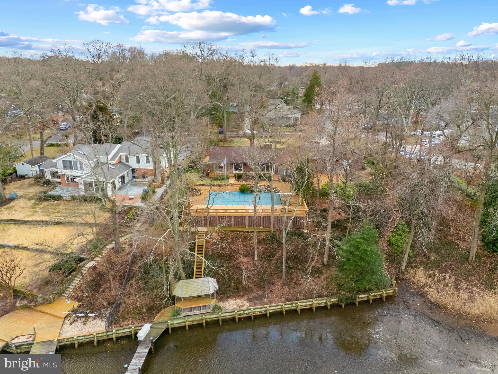 Spa Creek Waterfront with pool and private pier with 2 boat lifts! Perched above the serene shores of Spa Creek this 3 bedroom 2 bath home offers the perfect escape for year-round living, weekend getaways, or rental opportunities. Enjoy the home as-is or bring your architect to create the waterfront home of your dreams. Imagine waking up every morning to the gentle stirrings of the water fowl as the sun casts a warm glow across the water, feeling a sense of anticipation for the day ahead. Open the sliding doors onto the expansive waterside deck surrounding the refreshing pool; the perfect place to entertain or lounge on a sunny summer day. Savor your morning coffee in the cozy sunroom overlooking the pool and creek. The open floor plan of the Dining room and Living room with cozy fireplace are laid out to capture the views and to flow easily out to the fabulous exterior spaces. The galley style kitchen has plenty of cabinets, countertops and a breakfast nook. Adjacent to the kitchen is the expansive Family room, with rustic finishes including stone floor, exposed beams and pellet stove with stone surround. 3 bedrooms are nestled on the opposite wing of the home, including a waterside bedroom with sliding glass door leading to the pool and framing the water views. Step outside and immerse yourself in the tranquil surroundings, lounge under the waterfront pergola or continue out to the private pier and spend the afternoon fishing. Store all of your waterfront toys in the expansive storage area below the pool deck. Grab a water taxi directly from your dock and head down Spa Creek right into Annapolis for a night out on the town or venture off to some of the Bay's best cruising and fishing areas. Annapolis offers the perfect balance of small-town charm and big world sophistication. The tranquility of no-wake waters will delight boating enthusiasts with endless opportunities for recreation and the location provides quick and easy access to Annapolis, the Chesapeake Bay and beyond. Embrace the simple joys of the waterfront lifestyle and make this retreat your own. Welcome Home!