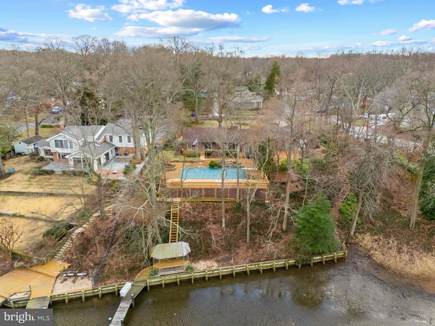 Spa Creek Waterfront with pool and private pier with 2 boat lifts! Perched above the serene shores of Spa Creek this 3 bedroom 2 bath home offers the perfect escape for year-round living, weekend getaways, or rental opportunities. Enjoy the home as-is or bring your architect to create the waterfront home of your dreams. Imagine waking up every morning to the gentle stirrings of the water fowl as the sun casts a warm glow across the water, feeling a sense of anticipation for the day ahead. Open the sliding doors onto the expansive waterside deck surrounding the refreshing pool; the perfect place to entertain or lounge on a sunny summer day. Savor your morning coffee in the cozy sunroom overlooking the pool and creek. The open floor plan of the Dining room and Living room with cozy fireplace are laid out to capture the views and to flow easily out to the fabulous exterior spaces. The galley style kitchen has plenty of cabinets, countertops and a breakfast nook.  Adjacent to the kitchen is the expansive Family room, with rustic finishes including stone floor, exposed beams and pellet stove with stone surround. 3 bedrooms are nestled on the opposite wing of the home, including a waterside bedroom with sliding glass door leading to the pool and framing the water views. Step outside and immerse yourself in the tranquil surroundings, lounge under the waterfront pergola or continue out to the private pier and spend the afternoon fishing. Store all of your waterfront toys in the expansive storage area below the pool deck. Grab a water taxi directly from your dock and head down Spa Creek right into Annapolis for a night out on the town or venture off to some of the Bay's best cruising and fishing areas. Annapolis offers the perfect balance of small-town charm and big world sophistication. The tranquility of no-wake waters will delight boating enthusiasts with endless opportunities for recreation and the location provides quick and easy access to Annapolis, the Chesapeake Bay and beyond. Embrace the simple joys of the waterfront lifestyle and make this retreat your own.  Welcome Home!