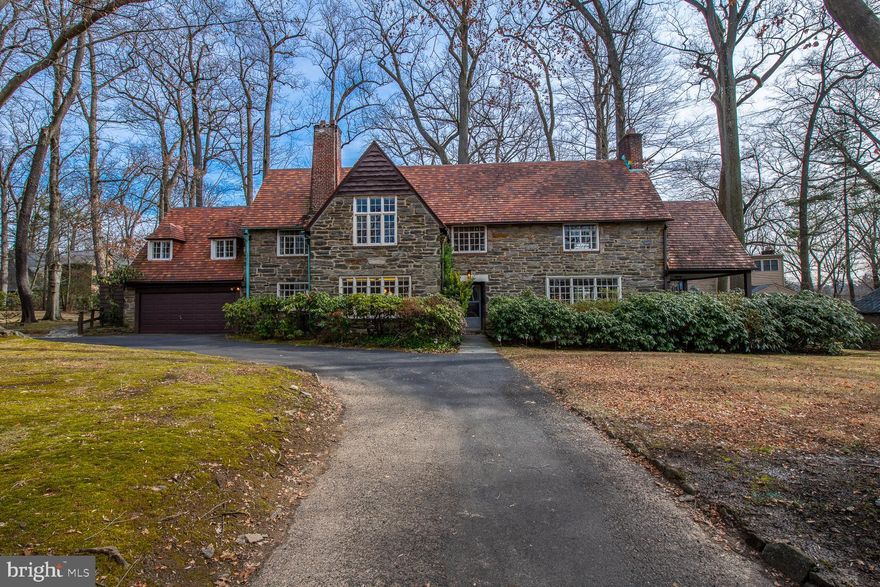 Virtual Tour    https://youtu.be/7_eZopCTUBA    Stately 1920's English Tudor stone home features 5 bedrooms, 3 full bathrooms,1 half bath and 1 quarter bath, on more than a third of an acre, with beautiful views from every window, attached two car garage, beautifully refinished random width hardwood floors throughout and a dramatic 2 story foyer with a magnificent oak staircase. A grand living room with working fireplace, deep window-sills and beautiful light throughout flows into a gracious stone & brick covered patio, offering ideal opportunities for entertaining throughout the downstairs. A large dining room compliments an open design kitchen with a double oven, separate island with second sink, vaulted ceilings, skylights, and windows with sliders to access the beautiful private backyard and gracious large slate patio. There is a cozy den next to the kitchen and a charming powder room. The second floor has 5 unique bedrooms with a Master Suite featuring 2 cedar closets, as well as built-ins with decorative custom painting and an en-suite bath. 3 additional bedrooms with ample closet space access a large, full hall bathroom with stall shower and tub. The 5th bedroom has both an entrance through a back staircase, as well as access to the main bedrooms, another private en-suite bath and large cedar closet, perfect for a guestroom or office. The third floor attic has easy access through a full staircase, and with a room-sized cedar closet for storage. A magnificent finished basement with custom painted wood beams, wood burning fireplace, separate storage area, and a separate laundry room with quarter bathroom, has both front and back staircases for access. Throughout, this lovely home features exquisite craftsmanship and fine details from a by-gone era. This home is conveniently located with a short train ride to Center City, and has quick access to all major highways. It is close to many major hospitals and medical centers and to a number of universities. It is also near local parks and recreation spaces, in a beautiful and quiet neighborhood, that retains a small town feel.