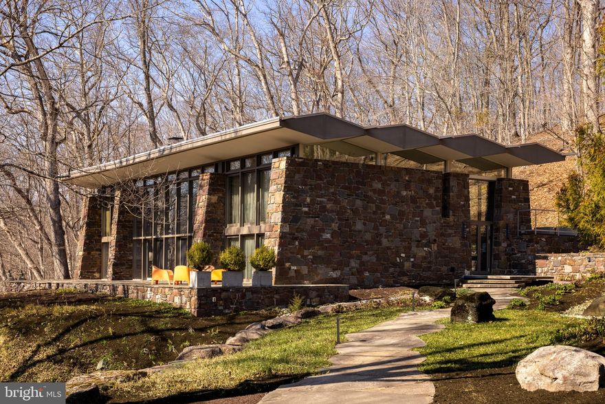 Originally constructed in 1959 and masterfully completed in 2014 following Paul Rudolph’s original architectural vision, The Fullam House stands today as a fully realized and enduring work of design, where historic integrity and modern refinement exist in perfect balance. The completion earned the prestigious AIA Bucks County Design Award for Excellence, recognizing the seamless integration of original architecture with thoughtful modern enhancements.
Conceived by Paul Rudolph, one of the most celebrated architects of the 20th century and former Chair of Architecture at Yale University, this extraordinary residence represents a rare and deeply personal work created during a pivotal moment in his ascent to international prominence. Known for his bold experimentation, sculptural forms, and leadership in the modernist movement, Rudolph’s work helped redefine American architecture in the postwar era.
Created for Judge John Fullam and his wife Alice, the home was born from a lifelong friendship that began during their years at Harvard. This was not a speculative project, but a deeply personal collaboration, where Rudolph was given creative freedom to explore new architectural ideas beyond his well-known Florida works.
At the request of the Fullam family, the home was intentionally never published during Rudolph’s lifetime, remaining an unpublished architectural work thoughtfully situated within the Bucks County landscape for decades. This allowed Rudolph to experiment with evolving concepts, including the interplay of mass and void, sculptural geometry, and environmental responsiveness, resulting in a design both ahead of its time and deeply connected to its surroundings.
Set on over 26 private acres, the property is seamlessly integrated into its natural environment, nestled into the hillside and overlooking a dramatic ravine. Constructed with Pennsylvania fieldstone, the residence reflects both Rudolph’s modernist philosophy and a nod to the local Bucks County vernacular.
Architecturally, the home is a study in light, structure, and spatial experience. A central open living pavilion forms the heart of the residence, flanked by private wings, creating a deliberate separation between public and private spaces. Floor-to-ceiling window walls, clerestory glass, and a distinctive floating roofline allow natural light to move dynamically throughout the home while framing uninterrupted views of the surrounding landscape.
Rudolph’s forward-thinking approach to environmental design is evident throughout. The sculptural roofline is both visually striking and functional, designed to block high summer sun while allowing winter light to penetrate deeply into the home, naturally warming the thick stone walls which then radiate heat into the space.
Inside, the residence offers approximately 3,500+ square feet, including 4 bedrooms and 3.5 baths, with living spaces that feel both expansive and intimate. The interplay of stone, glass, and wood creates a tactile richness, while the home’s multi-level design provides a unique spatial experience.
The 2014 completion faithfully realized Rudolph’s original intent while integrating modern systems and efficiencies. Surrounded by complete privacy, yet within close proximity to New Hope, Princeton, and major metropolitan areas, The Fullam House offers a rare convergence of architectural pedigree, historical significance, and modern livability.