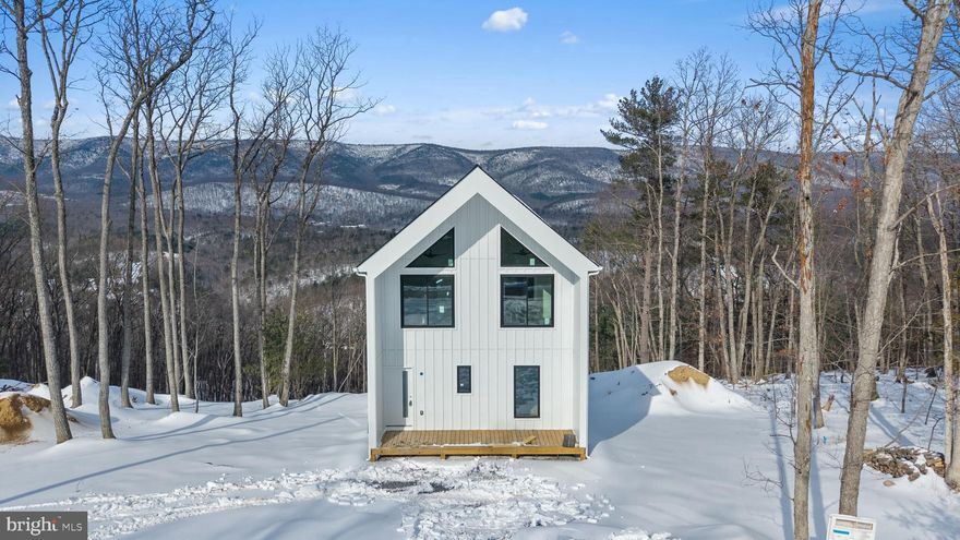 The elevated setting offers open sightlines and a sense of privacy, complemented by three expansive decks (two at 12' × 22' and one at 5' × 22'), a pre-constructed 400 sq ft amenity pad suitable for future hot tub or sauna installation (buyer to verify), a fire pit area, solar-lit stairs connecting deck levels, and Tesla-compatible EV charging. Inside, the home features clean Scandinavian-inspired design with floor-to-ceiling glass walls, open-concept living spaces, premium appliances, an upper-level loft with sweeping views, and a finished lower level that can function as additional sleeping space, recreation area, or flexible use room. A smart lock system supports convenient guest access and modern property management needs. Additional highlights include no HOA fees, private well service, a 3-bedroom rated septic system, and infrastructure in place for potential future amenity upgrades. With its combination of modern design, outdoor living space, and proximity to year-round recreation, this property presents a compelling option for buyers seeking a primary residence, second home, or short-term rental investment in a high-demand mountain setting.