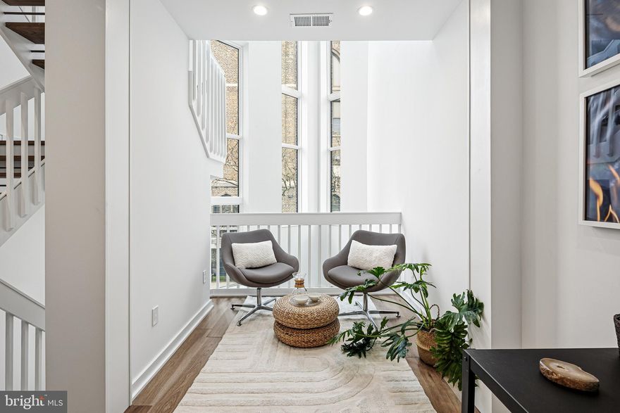 Rodger’s Row presents a thoughtfully designed residence where timeless mid-century influence is reinterpreted through a refined, modern lens. This is a home defined by intention—where clean lines, natural light, and functional elegance converge.

At the rear, two off-street parking spaces provide rare convenience, complemented by a private garden that serves as a quiet extension of the living space. Oversized sliding glass doors create a seamless indoor-outdoor connection, enhancing both light and livability. Inside, the main level unfolds with a sense of openness and calm. A dramatic four-story atrium draws natural light deep into the home, creating a soft, ever-changing ambiance throughout the day.

The living and dining areas are inviting yet understated, designed for effortless gathering and everyday comfort. Just beyond, the kitchen balances form and function with a curated blend of warm finishes and modern detailing.

The second floor offers a flexible, open-concept level that adapts to a variety of needs—whether a home office, library, or secondary living area. Generous front-facing windows, transom details, and thoughtful architectural elements create a sense of continuity and lightness. This level also features two bedrooms and two bathrooms connected by a well-considered Jack-and-Jill balcony.

The third-floor primary suite serves as a private retreat. Spacious and serene, it is complemented by a discreet coffee bar, space for integrated wine storage or a writing nook, and direct access to a private balcony. Pocket doors provide separation when desired, allowing the space to transition seamlessly between openness and privacy.

Above, a full roof deck offers sweeping 360-degree views and an elevated setting for quiet evenings or intimate entertaining.

The lower level introduces a calm, versatile retreat with a generous rec room, a fully equipped guest bedroom and bathroom, and ample storage. Laundry is conveniently located on the second floor.

Positioned in the heart of Fishtown, just moments from Adaire School and the neighborhood’s most notable amenities, Rodger’s Row offers a rare opportunity to own a home that balances architectural character with modern sophistication. A residence designed to endure—both in style and in function.