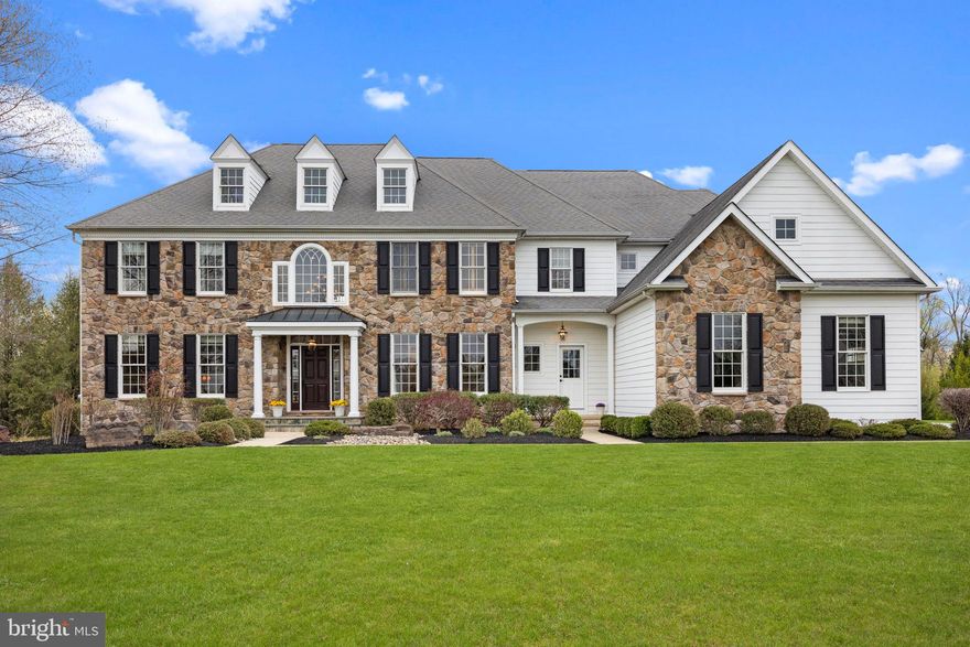 This stately custom home, nestled in a private enclave of just twenty-nine luxury residences within the prestigious Belamour community of Upper Makefield, is being offered for the first time. Located in the highly acclaimed Council Rock School District, this exceptional property combines timeless elegance with unparalleled exclusivity. Set on a serene 1.3-acre lot, this home is ideal for outdoor entertaining with a sparkling pool and spa, a bluestone patio, and an expansive Brazilian walnut deck—perfect for enjoying the breathtaking landscape. The grand stone-front residence offers every modern comfort with 5,400 square feet on the main and upper levels, an additional 1,400 square feet of finished living space on the lower level, and a spacious four-car garage. 
A dramatic two-story entryway with a sweeping staircase and gleaming hardwood floors sets the tone for this elegant yet inviting home. The foyer is flanked by the formal living and dining rooms creating an ideal setting for both intimate and large gatherings. Culinary enthusiasts will be delighted by the expansive kitchen featuring abundant off-white cabinetry, granite countertops, double ovens, a gas cooktop, warming drawer, and butler’s pantry.  The large island invites both gathering and collaborative cooking. Adjacent, the sunroom offers a peaceful morning retreat with panoramic views, while the welcoming great room—anchored by a cozy fireplace—beckons in the evening. A private home office provides a quiet retreat for remote work or creative pursuits. The conveniently located mudroom includes custom cupboards, cubbies, and a built-in desk, connecting directly to the four-car garage—ideal for organizing outdoor gear and equipment.
Front and rear staircases lead to the second level featuring the luxurious primary suite with trey ceiling, two walk-in closets, a spacious bath with jacuzzi tub, separate vanities, and classic and neutral finishes.  Four additional well-sized bedrooms, two with Jack and Jill bath, an additional bath, and a large attic space for storage or various other uses complete this level.
The expansive lower level, features a convenient half bath and endless flexibility for media, gaming, fitness, hobbies, and entertaining, with direct access to the patio and heated pool. Spend summer days lounging by the pool and spa, and enjoy al-fresco dining on the deck as the fireflies twinkle in the twilight.
This exceptional estate property, offers luxury, comfort, and timeless style in the heart of bucolic Bucks County—just minutes from historic Newtown Borough, New Hope, and Washington Crossing. Discover renowned restaurants, charming boutiques and galleries, live theatre, golf courses, and picturesque parks—all just moments away.