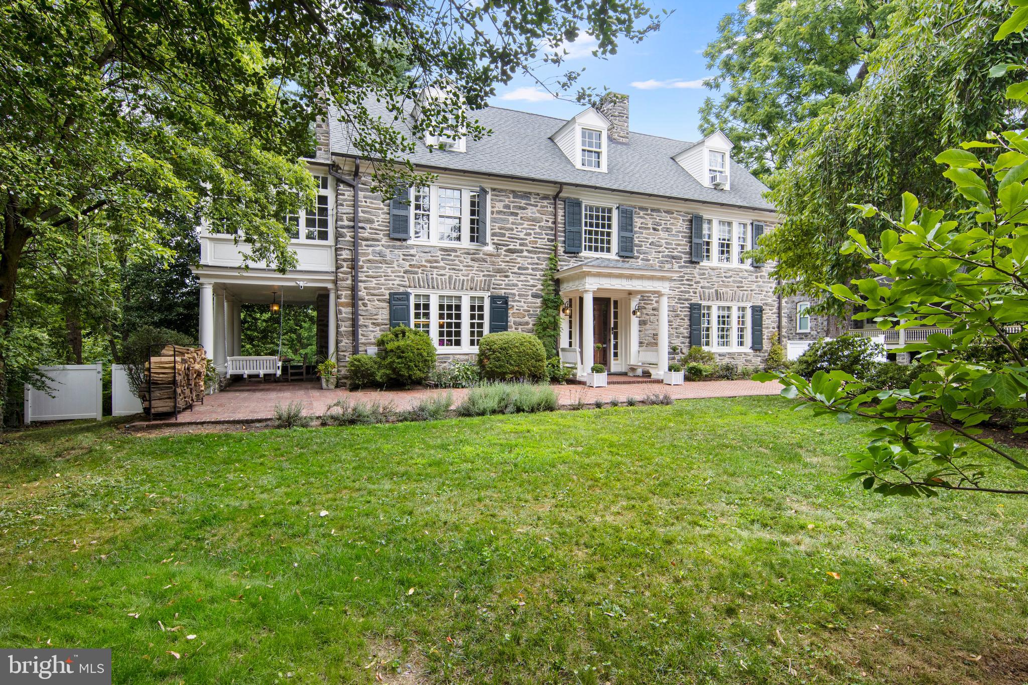 Welcome to 117 Carpenter Lane, a truly remarkable Colonial Revival Estate with a rich history dating back to the early 1900's. Originally built for the family of Sydney L. Wright, a prominent banker, this quintessential estate exudes timeless elegance and modern luxury. With four finished levels, six bedrooms, and four and a half baths, this home provides an abundance of space and modern amenities. Notable features of the home include a striking circular staircase, lofty 10-foot ceilings, and exquisite maple flooring on the first floor, complemented by yellow pine on the upper levels. The current owners have taken great care to elevate this home to new heights, with substantial upgrades including a modernized whole-house electrical system (Lutron), efficient mini splits for heating and cooling, a new sewer line, and extensive landscaping including the addition of green house and gardener shed. Custom lighting throughout the home beautifully harmonizes the old-world charm with modern appeal. As you walk down the front brick walkway, you're welcomed by sitting benches and a Dutch door. Step inside the gracious foyer to be greeted by an elegant staircase, a center fireplace, and handsome mill work. Through the double doors, the living room, with its custom built-in bookshelves and handsome wood burning fireplace, sets a luxurious tone. Out the French doors, the covered patio offers a refined setting for alfresco dining and entertaining. The expansive formal dining room soaked in natural light, currently used as a dining room and family room sets the stage for future gatherings. The carefully curated eat-in kitchen is a chef's delight, featuring rustic Moroccan tumbled limestone flooring, complemented by top-of-the-line Wolf professional range/hood and oven, and Jenn-Air electric convection oven. The extra prep sink is an added bonus. The wrap-around raised deck off the kitchen offers ample space for daily enjoyment and entertaining. The back stairs off the kitchen adds an extra layer of functionality. Ascending to the second floor, the private master suite is a true retreat boasting a cozy fireplace and a spacious changing room. The captivating sun porch with radiant heat and elegant porcelain flooring leaves a lasting impression. The ensuite bath offers a dual vanity and glass shower. Across the hall is the second bedroom, complete with built-in drawers and an ensuite bath featuring a jetted soaking tub and glass shower. The third bedroom, located on the left wing, is perfect for guests, offering ample space and a private full bath for their stay. Convenience is key with the laundry room also located on this level. Venturing to the third level, you'll discover a spacious living area with three generously sized bedrooms and a beautifully updated hall bath, offering a world of possibilities for personalization. The modern finished lower level is a true haven for relaxation and entertainment, with ceiling heights ranging from 7'1" to 7'8". The state-of-the-art home gym features a built-in sound system for an enhanced workout experience. Enjoy the lounge area with a custom-built in bar and sitting area that is perfect for hosting friends and family. The family room, complete with a barn door offers generous space for movie nights or your next watch party. As you step into the fenced-in backyard, you'll discover a private paradise for gardening enthusiasts. The greenhouse is all set for your starter seeds, getting you ready for your next harvest. The standalone cedar gardener's shed offers versatility and convenience. The extensive raised garden beds and plantings are sure to leave you in awe. Hang out at the outdoor fire pit with views of the lush gardens. Walkable to all things Mt Airy. Easy access to Center City, Chestnut Hill, and the Wissahickon Hiking/Biking Trails. Roof has 30 year warranty.