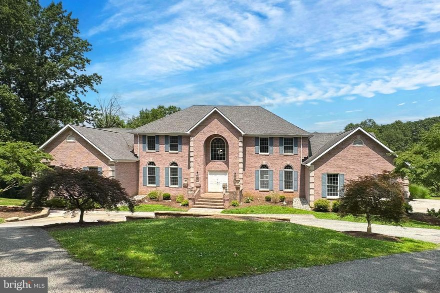 Just 25 minutes from the vibrant heart of Baltimore City, this home demonstrates the perfect harmony of spacious style, unmatched acreage, and unbeatable convenience. Tucked at the end of a cul-de-sac on an expansive 7.612 acre, tree-framed lot (the largest in the neighborhood!), this symmetrical all-brick colonial makes a striking first impression. Round the circular driveway, enter the front door, and you’ll be immediately wowed by the 2-story entryway bookended by a formal sitting room and spacious dining room. A nearby half bathroom adds convenience. The living room makes a statement with its soaring vaulted ceiling, second-floor balcony overlook, a dramatic brick fireplace and oversized windows boasting picturesque views of your private, wooded lot. The views of autumn foliage are simply breathtaking! The adjacent gourmet kitchen is a chef’s dream, featuring a center island, expansive granite countertops, abundant cabinet storage, and casual dining space. When it’s time to unwind, the luxurious Primary Suite is the ultimate retreat with its roomy bedroom, dual walk-in closets, French doors to a flexible office or nursery, and a magazine-worthy, spa-like bathroom with a soaking tub, independent vanities, standing shower, and linen closet. At the opposite end of the main level is an additional bedroom and full bathroom well-suited for in-law or guest quarters. Or, use it like the sellers – as a walk-in pantry and hall bathroom, convenient to the garage entrance. Upstairs, four sizable bedrooms and two remodeled full bathrooms offer space for family and guests alike. An enormous lower level adds a surplus of space with a second kitchen, den for movie nights or game-day gatherings, home gym with full bathroom and direct access to a private patio with 8-person salt water hot tub, bonus room, and two huge storage spaces – easily convert one to a workshop or studio, the sky’s the limit! A 3-car garage solves all your parking needs and a large rear deck provides a place to relax outdoors. Equally remarkable as the home itself, is the property. This one-of-a-kind nature lovers’ paradise flaunts a unique blend of flat open yard, adventure-ready terrain ideal for hiking, walking your dog, or 4-wheeling, and a shady, lower forest perfect for exploration, a fire pit, treehouse, and/or zip lining course, and endless outdoor fun. Dreaming of running, biking, fishing, tubing, or kayaking? The nearly 20-mile NCR Trail is just 1.4 miles from your new home! Pride of ownership shines in the countless enhancements made by the seller in the last four years including : new LVP flooring throughout, updated trim, painting throughout, new modern light fixtures, two new tankless water heaters, 1 new heat pump (this home has 3 zone heating/cooling!), a new well, renovated Primary Bathroom, upgrades to all other bathrooms and the kitchen, and substantial landscaping revisions. Top-tier schools are the cherry on top! What are you waiting for? Schedule a showing today!