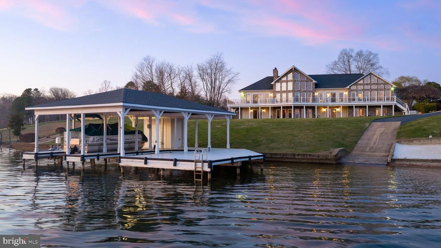 Experience unparalleled luxury and panoramic lake views at arguably the finest lot on Lake Anna. This custom-built masterpiece exemplifies exceptional craftsmanship and timeless elegance—a true showstopper that will be the centerpiece admired by all who pass by on the water. This is not just a home; it’s a legacy at Lake Anna. Set on the shores of the public side of the lake, this residence showcases some of the most coveted, unobstructed views, complete with unforgettable sunsets. At the heart of the home, the grand great room features soaring vaulted ceilings, dramatic floor-to-ceiling windows framing miles of breathtaking water vistas, and a striking stone gas fireplace that anchors the space in warmth and sophistication. Offering 5 spacious bedrooms and 6.5 luxurious baths, the open-concept floor plan flows seamlessly across gleaming hardwood floors. The primary suite offers sweeping lake views, while every bedroom enjoys its own private bath, ensuring comfort and privacy for family and guests alike. The lower-level walkout basement is an entertainer’s paradise, complete with an expansive family room, recreational area, full-sized commercial bar, pool table, and additional bedrooms—all accented by walls of windows that capture the stunning lake scenery. Every corner of this home is designed for effortless indoor-outdoor living and entertaining. Step outside to meticulously landscaped grounds leading to your private sandy beach and covered boathouse, featuring dual slips with electric lifts, jet ski lifts, storage, sun deck, and private boat ramp with deep water access (10’ at dock’s end). The shoreline is protected by concrete bulkhead ensuring lasting durability. An oversized garage accommodates four vehicles or additional boats, complemented by a paved circular driveway. A generator conveys for peace of mind, high speed Xfinity Comcast internet available and most furniture conveys! This is a truly rare opportunity to own a waterfront estate without HOA restrictions—a home that defines the ultimate Lake Anna lifestyle. Schedule your private showing before this extraordinary gem is gone.