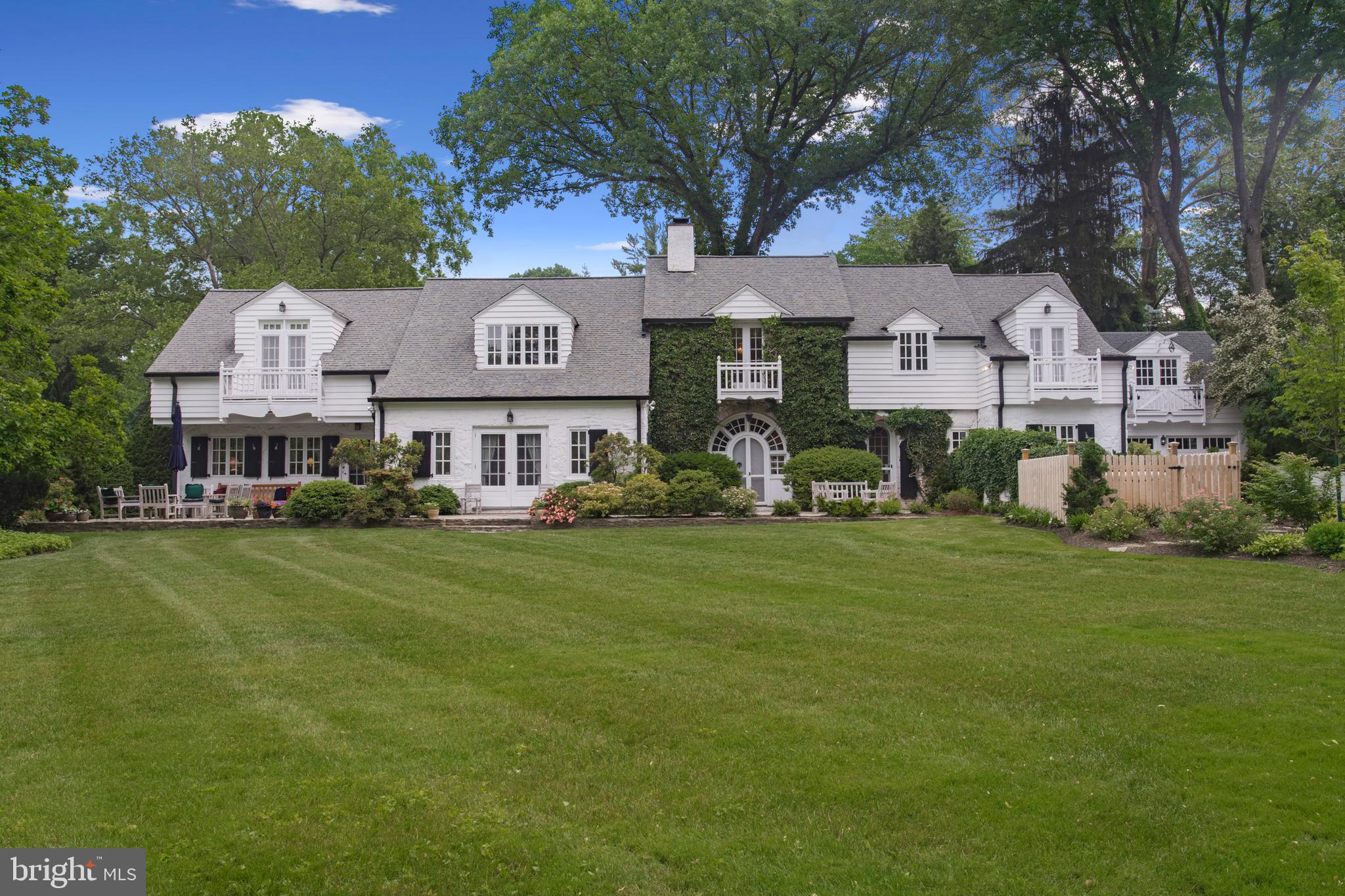 Welcome to 711 Pennstone Road! Situated on pristine grounds in northside Bryn Mawr, "The Bank Barn" was originally a stable/barn on the historic Harriton Estate and was converted to a “carriage house” home in the 1930s. Beautifully maintained, and thoughtfully expanded and updated both inside and out by the current owners, this special home is truly a must-see for anyone looking on the Main Line. As you enter through the magnificent arched front door, you will notice the original details and craftsmanship, including reclaimed heartwood pine random-width flooring and antique hardware throughout. The living room features built-in bookshelves, a fireplace, and a Dutch door leading to the back patio and fenced-in yard. Off the living room through arched doorways is an office / sunroom with French doors to the terrace at the front of the home and cabinetry designed to hide all the conveniences of a modern office when not in use. Also off of the living room is a family room / additional office, which also includes hideaway office cabinetry and access to the front yard terrace. The dining room, with ample light from an arched glass door, features additional built-in shelving and cabinetry and leads into the den / breakfast area with a bay window seat, a door to the backyard / patio, and a convenient powder room. The chef's kitchen designed in the farmhouse style, includes an eat-in island, custom cherry cabinets, radiant wood floors and high-end appliances: a Thermador commercial-style range with pot-filler and hood vent, and new Miele dishwasher, Bosch double wall ovens and Sub-Zero refrigerator. The kitchen flows into the mudroom with terracotta flooring from an Italian church, a pantry and access to the finished basement and the driveway with 2-car garage. The second floor of the home features a spacious owner's suite with walk-in closet, additional closets, a balcony with French doors, and a Portuguese tiled en-suite bathroom with a soaking tub and stall shower. Off of the hallway is an additional bedroom with built-ins and en-suite bathroom. This room includes double pocket doors so it could act as an extension of the owner's suite, or as its own private bedroom. Also off the hall is an additional bedroom with a deep closet and a window seat which flows into a 'jack-and-jill' hand painted tile bathroom with shower / tub combination and then leads into the den suite - a perfect playroom or common den area - which is also off the main hall. This room opens into another bedroom, with a window-seat and French doors to a balcony. The newly renovated basement is finished with a tiled floor and recessed lighting and includes abundant storage, a work area, a living/project area, and a full laundry room complete with cabinetry and counterspace, an extra refrigerator and sink. Above the 2-car garage is an additional heated, finished room which is currently being used as storage but could accommodate many different uses. Other notable features of this wonderful home include: a high-efficiency zoned gas heater, a whole house generator, a leak-defense system and a recently redesigned backyard oasis with a two-tiered wall garden. The multiple patios and outdoor areas and its interior layout make the home ideal for entertaining. Located in desirable Lower Merion Township and within close proximity to the shopping, restaurants, and the train station in Bryn Mawr, this one-of-a-kind home has it all!