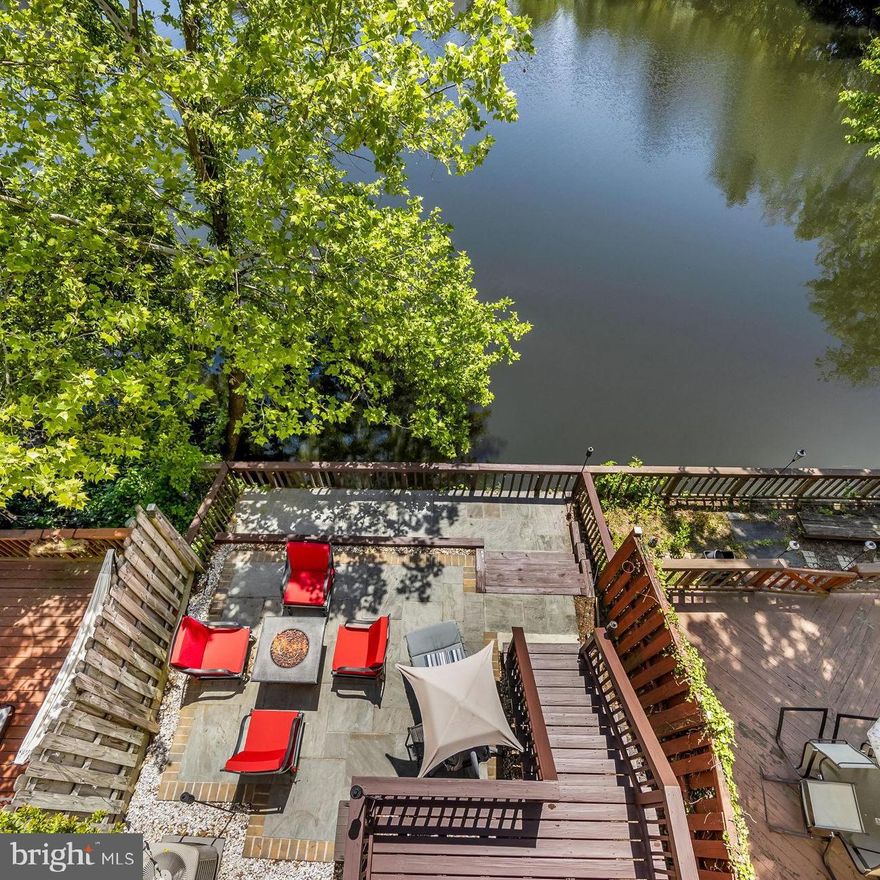 Rarely available waterfront townhome in Falls Church offering over five levels of spacious, light-filled living with beautiful lake views throughout. This beautifully maintained 3 bedroom, 3.5 bath home features soaring ceilings, new carpet throughout, and an open-concept layout designed for both comfortable everyday living and effortless entertaining. The updated, open kitchen opens to the dining area overlooking the dramatic living room with cathedral ceilings and expansive windows framing the water views and features white shaker cabinetry, quartz countertops, stainless steel appliances, pantry storage, and access to a private upper-level deck.  Doors lead to a spacious deck perfect for morning coffee or evening gatherings overlooking the lake with steps that descend to the flagstone patio below, an ideal setting for outdoor dining and relaxing by the water.
Upstairs, the spacious primary suite offers cathedral ceilings, skylights, a custom closet, and a beautifully renovated ensuite bath with dual vanities and a walk-in shower. A second upper-level bedroom features dual closets, and its own ensuite bath. The lower level includes a private third bedroom guest suite with full bath, while an additional loft area with built-in desk space provides the perfect work-from-home setup. Located in a gated community with clubhouse and pool, this exceptional home offers a peaceful waterfront retreat just minutes to Tysons, Mosaic District, I-495, Inova Fairfax Hospital, shopping, dining, and major commuter routes.