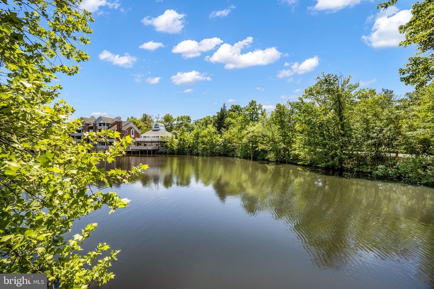 Rarely available waterfront townhome in Falls Church offering over five levels of spacious, light-filled living with beautiful lake views throughout. This beautifully maintained 3 bedroom, 3.5 bath home features soaring ceilings, new carpet throughout, and an open-concept layout designed for both comfortable everyday living and effortless entertaining. The updated, open kitchen opens to the dining area overlooking the dramatic living room with cathedral ceilings and expansive windows framing the water views and features white shaker cabinetry, quartz countertops, stainless steel appliances, pantry storage, and access to a private upper-level deck.  Doors lead to a spacious deck perfect for morning coffee or evening gatherings overlooking the lake with steps that descend to the flagstone patio below, an ideal setting for outdoor dining and relaxing by the water.
Upstairs, the spacious primary suite offers cathedral ceilings, skylights, a custom closet, and a beautifully renovated ensuite bath with dual vanities and a walk-in shower. A second upper-level bedroom features dual closets, and its own ensuite bath. The lower level includes a private third bedroom guest suite with full bath, while an additional loft area with built-in desk space provides the perfect work-from-home setup. Located in a gated community with clubhouse and pool, this exceptional home offers a peaceful waterfront retreat just minutes to Tysons, Mosaic District, I-495, Inova Fairfax Hospital, shopping, dining, and major commuter routes.