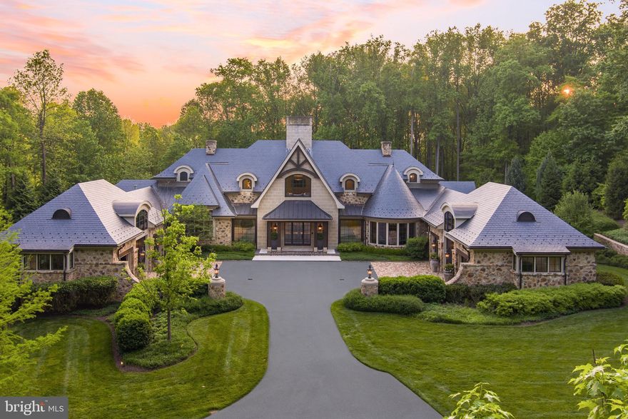 Welcome to a true masterpiece in the gated, prestigious Caves Valley Golf Club. This impressive custom stone estate presents five bedrooms, five full and three-half baths and sits on over five acres of meticulously manicured grounds. The exquisite residence was designed by renowned architect Vincent Green and crafted by Pyramid Builders showcasing incredible architectural design and bespoke details that lend refined touches throughout the nearly 13,000 square feet of gracious, comfortable living spaces. Nestled in the picturesque rolling hills of Greenspring Valley, this residence offers a truly unparalleled living experience. Upon arrival, a stately private drive opens up to a grand stone facade and courtyard centered around a commanding front entry with a six-car garage. The home is entered through custom iron doors that introduce you to dramatic foyer with an impressive double sided fireplace. The captivating main level features an oversized great room with floor to ceiling windows overlooking the pool. Adjoining the great room, you'll be immediately drawn to the centerpiece of the room—a stunning glass enclosed wine cellar. This architectural marvel showcases a vast collection of wine bottles seemingly floating in mid-air, creating a mesmerizing display allowing you to admire the beauty of your wine collection. Beneath your feet, the floor is adorned with exquisite translucent marble adding a touch of opulence. Surrounding the wine room, you'll discover a tastefully designed bar area, where you can indulge in wine tastings or savor a glass of your favorite vintage. The world class kitchen captures every luxurious amenity including professional grade appliances, oversized island, dual refrigerators, walk-in pantry and breakfast area with views of the gardens and outdoor pool. A formal dining room that provides elegant setting for hosting 12 or more guests with a butlers pantry. Retreat to the deluxe first floor primary bedroom suite which presents a gold leaf barreled ceiling and a seating area leads into the luxurious marble spa bath with "his and hers" vanities, a soaking tub, and double sided walk-in shower with vertical spa and rain shower. The suite is outfitted with his and her custom walk-in closets. A formal home office finished in rich cabinets, sleek gas fireplace provides an ideal setting to work from home. Two mudrooms, additional work station, and three half baths complete this expansive main level. Ascend up the curved staircase to the upper level to find a family room, three well-appointed guest bedrooms each with its own en-suite bathrooms and a 2nd laundry room. Indulge in the ultimate relaxation and entertainment in the impeccably finished lower level, boasting a state-of-the-art Trackman golf simulator, media room adjoined by a stunning bar for entertaining, an exercise suite and spacious guest or au-pair suite with full bath. With multiple gathering spaces and an abundance of natural light, this level is designed to impress and cater to your every desire. The entire first floor opens seamlessly to the expansive outdoor entertaining areas with a blue stone terrace, fire pit, plunge pool, and an outdoor grilling center equipped with custom lighting and sound. The comprehensive land and hardscape plans provide for enjoyment of the outdoor living experience as much as the indoor. An elevator services three levels and a smart house system by Crestron controls lighting, music and security systems. Caves Valley Golf Club Residences offers an extraordinary lifestyle that combines the allure of luxury living with the beauty of a world-class golf course. Live in an exclusive community in a coveted destination. Imagine stepping out of your home and onto the greens for a round of golf at your leisure. Whether you are an avid golfer or simply appreciate the beauty of an exquisite community, this extraordinary living destination provides an unrivaled experience.