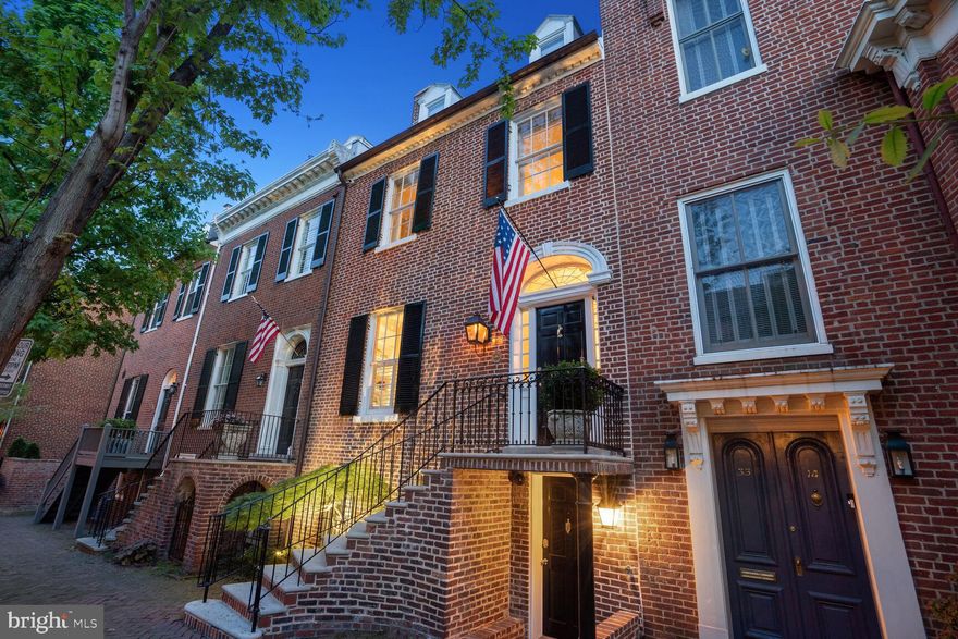 Elegant Federal townhouse built in 1818 located in Georgetown's sought-after West Village, just blocks away from the shops and restaurants of Wisconsin Ave. Ideal for entertaining, Main Level features a semi-open floor plan, opening to large Foyer and Entry Hall with original wide-plank heart pine wood flooring. Gracious Living Room with original fireplace and stone hearth connects seamlessly to bright Dining Room which enjoys access to rear Terrace through French doors. Service Kitchen (in addition to Full Kitchen in LL) leads to deep, private flagstone Terrace/Pool. Lower Level with separate front/rear access and new ceramic floors includes updated Full Kitchen with large center island and Pantry, Storage Closet with Wine Fridge, spacious Family Room with fireplace and custom built-ins & updated Half Bath. Second Level Primary Suite with fireplace, large walk-in Closet, en-suite Full Bath with dual vanity, separate tub & shower, + water closet; Level also includes private Office with Balcony. Third Level offers 3 additional Bedrooms, each with their own Closet, which share a Full Bath. Complete with Rear Alleyway Access to 1-Car Secured Parking.