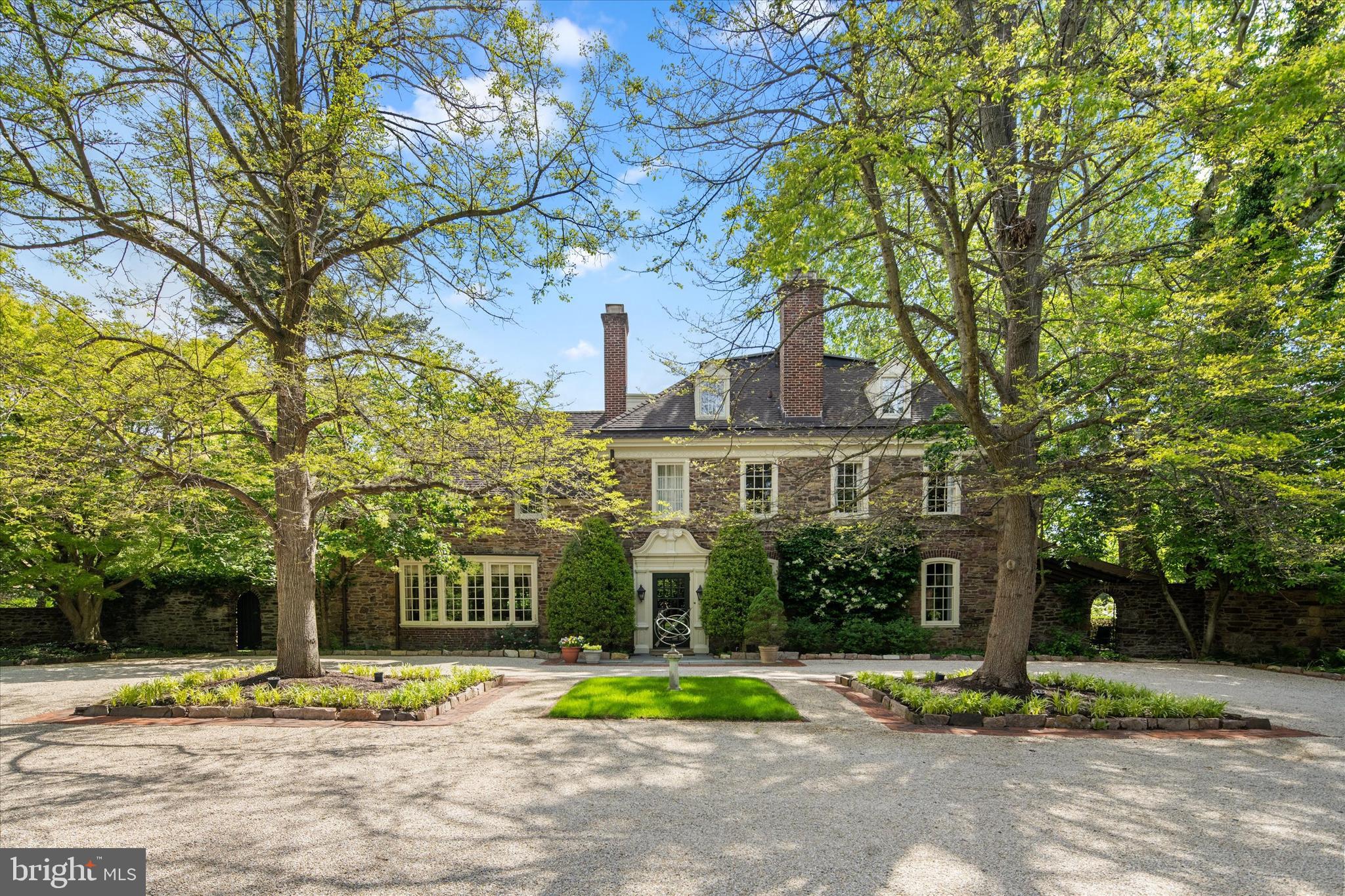 Introducing Gypsy Run, an enchanting estate nestled in the heart of Gwynedd Valley, set on over four private acres. A long, tree-lined driveway winds past a tranquil pond and reveals an impressive stone manor that exemplifies the craftsmanship and timeless elegance of a bygone era.
Steeped in history, the home showcases exquisite original details, including handcrafted Mercer tilework, wide-plank hardwood floors, deep-set windowsills, intricate millwork, arched doorways, grand crown moldings, and original stone fireplaces.
A stately Mercer-tiled foyer sets the tone, offering a gracious welcome. To the left, a formal dining room features a granite fireplace and a large bay window overlooking the motorcourt. To the right, the formal living room boasts a coffered ceiling, fireplace, and French doors opening to a sweeping slate patio. Adjoining this space is a richly paneled study with built-in shelving and a fireplace.
At the heart of the home is a sun-filled kitchen and a thoughtfully designed breakfast room addition, with floor-to-ceiling windows framing panoramic views of the grounds and pond. A large center island, professional-grade appliances, and a cozy gas fireplace create an inviting yet sophisticated space for daily living. The adjacent butler’s pantry, complete with marble countertops, a secondary dishwasher, and a beverage refrigerator, offers abundant storage and ideal support for entertaining. A rear mudroom provides access to a private two-bedroom inlaw or nanny suite.
Upstairs, the bright and expansive primary suite is a private retreat, featuring a sitting room with fireplace, a private office, a walk-in closet, and a renovated en-suite bath with a walk-in shower—plus a second, private full bathroom. A secondary suite offers comfort and privacy, while a hallway lined with closets and a laundry room leads to a third spacious bedroom with en-suite bath and walk-in closet. The third floor includes two additional bedrooms, a full hall bath, a large recreation room, and generous storage spaces.
The outdoor spaces are equally captivating. An expansive slate patio overlooks the scenic grounds, peaceful pond, and in-ground pool, surrounded by lush gardens and mature trees that lend the feel of a secluded country retreat. A charming springhouse, partially repurposed as a cabana, and a newly built three-car garage with ample additional parking complete this extraordinary property.
Ideally located just a half mile from the Gwynedd Valley train station and minutes from local shopping and dining, Gypsy Run is a rare offering—an exceptional estate that honors its historic legacy while embracing modern comfort and refined living.