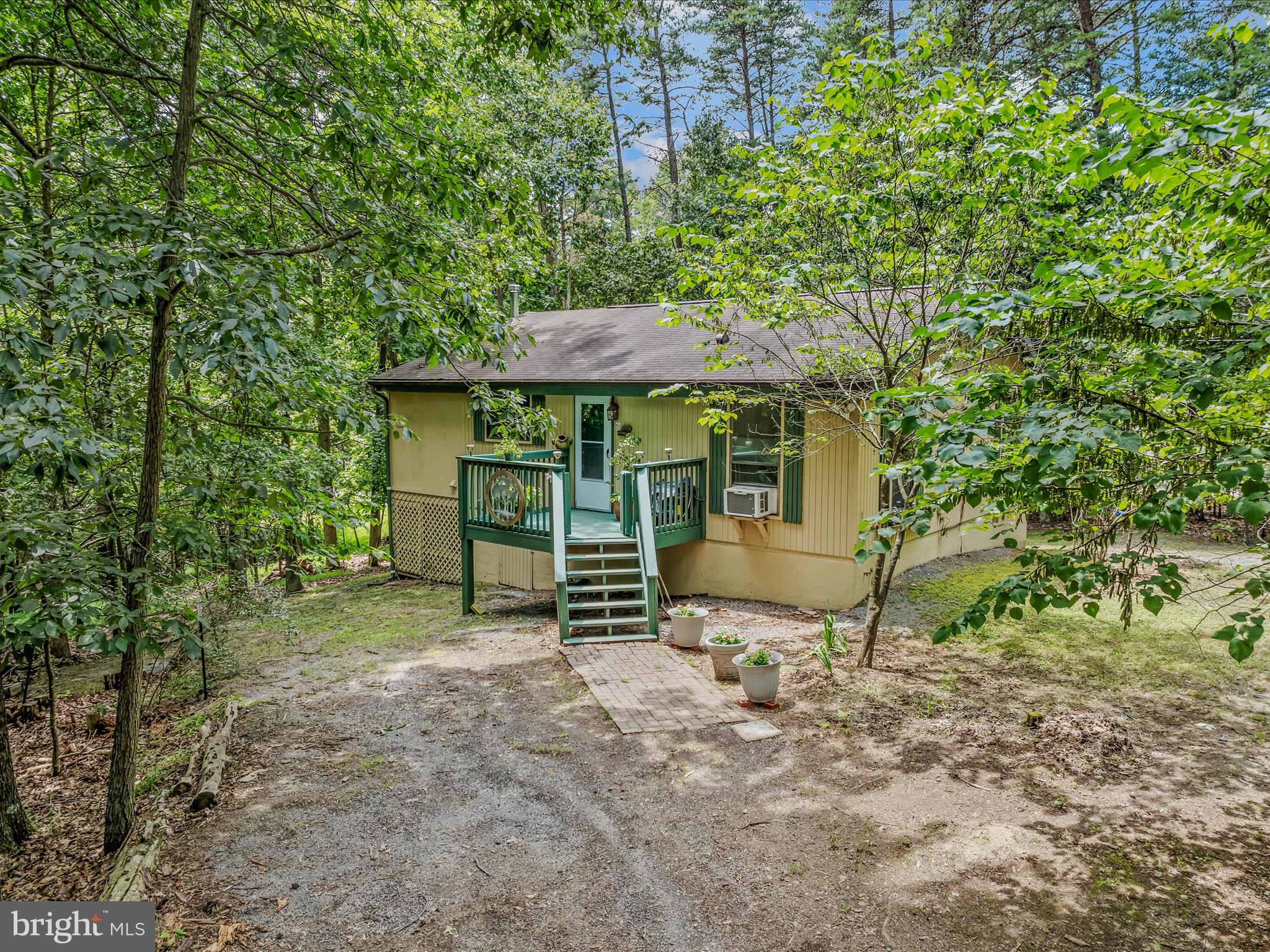 Cozy 2-bedroom cabin nestled in the Walden Woods section of The Woods Resort community. Follow the walkway to the freshly painted porch and then step inside to enjoy an open floor plan with a charming corner fireplace. The sunroom features a woodstove and a conveniently tucked-away laundry area for easy access. The seller has found the sunroom to be an ideal inspiration spot for her paintings. This space allows you to relax and enjoy the surrounding nature with your morning coffee. The cabin has been freshly painted, and new flooring has been installed. In case of a power outage, the home includes a generator that will convey with the property.