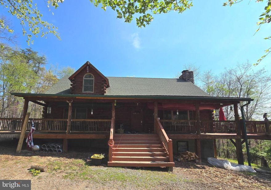 RUSTIC LOG HOME ON 20+ ACRES!!!  This beautiful cabin features rough-cut logs inside and out.  The main level showcases an expansive great room with vaulted ceilings, wood flooring, and a stone hearth wood-burning fireplace.  Just off the living room is a large kitchen and dining area.  The kitchen has a built-in electric stove and microwave, tile countertops, and island with electric cooktop.  Also on the main level, you will find a primary suite with a built-in safe in the bedroom and a spacious bathroom with dual vanity, soaking tub, and stall shower.  The home's upper level features two additional bedrooms, a full bathroom with tile floors, a stall shower, and an open loft overlooking the great room.  The basement is ready for you to finish and make your own with rough-in plumbing for an extra bathroom, a large space for a family room with a woodstove already installed, and a separate room with a large bar!  Also positioned on the property is a new, large 3-car metal garage with concrete flooring already poured.  Bring your imagination and handyman skills to complete/restore this log home to its full potential!