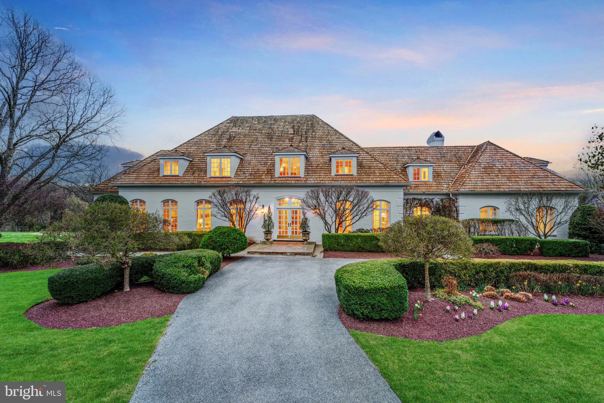 Price improvement! Don't miss this incredible home. It is not often a home with this level of craftsmanship, space, and charm—set on a superior two-acre lot backing to parkland—becomes available. Located in the coveted Wootton school cluster, this expansive and elegant residence offers over 10,000 square feet of beautifully designed living space at the end of a quiet cul-de-sac, offering both privacy and connection to nature.
The home welcomes you with a grand two-story foyer, setting the tone for the thoughtfully designed interior. The formal living room features hardwood flooring, crown molding, and floor-to-ceiling windows that flood the space with natural light. Adjacent is a dining room equally refined with crown molding and wall-to-wall windows, ideal for hosting gatherings both large and small.
A butler’s pantry with additional cabinetry leads to the heart of the home: a gourmet kitchen equipped with granite countertops, a center island, Sub-Zero refrigerator, gas cooktop, abundant wooden cabinetry, and a built-in desk space. A sliding glass door opens to the expansive deck, while the kitchen sink overlooks the backyard and serene wooded views, creating a perfect blend of function and beauty.
Off the kitchen is a charming breakfast area with two-story ceilings and an oversized stone fireplace—a stunning focal point for everyday living. A back staircase leads conveniently to the upper level.
At the center of the home is the great family room, featuring vaulted ceilings, a striking fireplace with a wooden mantle and stone surround, and tall windows that frame the natural landscape. French doors lead directly to the deck, creating a seamless indoor-outdoor flow. A wet bar with a beverage refrigerator and sink makes this space ideal for entertaining.
Also on the main level is a powder room, a dedicated office, and a laundry/mudroom off the three-car garage, complete with additional cabinetry and storage.
The main-level primary suite is a true retreat. The bedroom includes two walk-in closets and French doors leading to a sitting room with vaulted ceilings, a gas fireplace, and its own private deck. The en suite bathroom features dual vanities, a large soaking tub, a separate glass-enclosed shower, and heated tile floors for year-round comfort.
Upstairs, you'll find four generously sized bedrooms, each offering vaulted ceilings and custom built-in window benches that add charm and character. Two large hall bathrooms provide ample space for family or guests. An additional upper-level space is perfect for a home office, playroom, or potential bedroom. At the end of the hall is an expansive bonus room above the garage, outfitted with extensive built-in cabinetry, offering ultimate flexibility for your lifestyle needs.
The fully finished walk-out lower level is designed for multi-generational living or extended stay guests. It includes a second full kitchen, a spacious recreation room with a gas fireplace, doors leading to the backyard, a bedroom with full en suite bathroom, exercise room, two large storage rooms, an additional set of washer and dryer, and even a separate garage—perfect for yard equipment or workshop space.
One of the home’s most unique and desirable features is the private path from the backyard that connects directly to the Muddy Branch Trail, offering direct access to miles of scenic parkland—right from your own backyard.
This home is a private retreat surrounded by nature, yet still incredibly convenient to Kentlands, Downtown Crown, Rio, and major commuter routes—the best of both worlds!