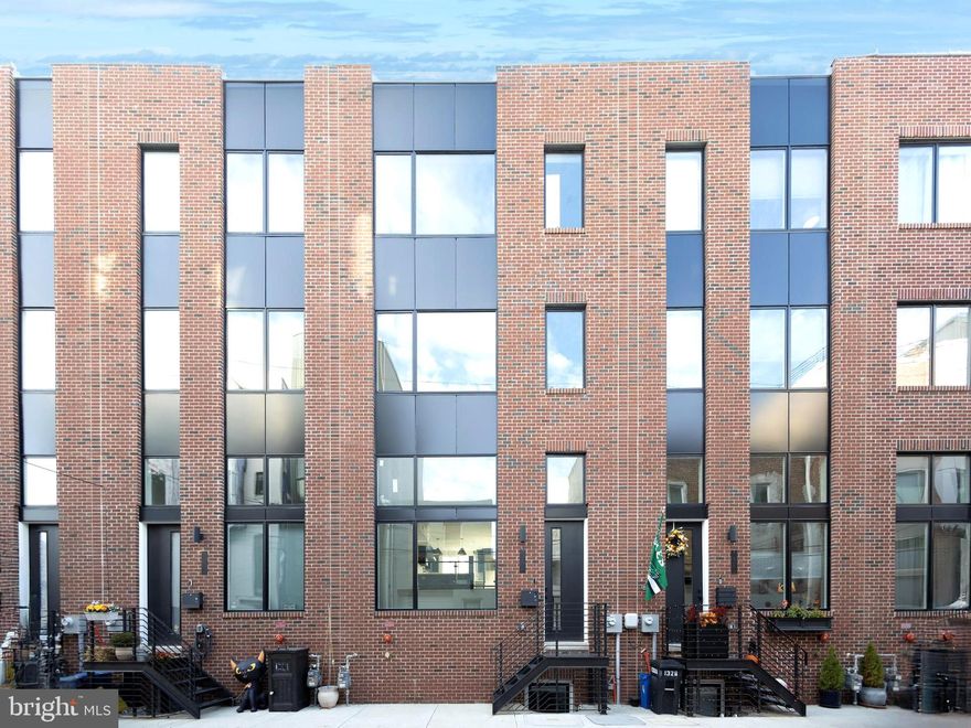 COMING SOON — 1328 S. Woodstock Street! Located on a charming cobblestone street in the premier Wharton Court community, this luxury 20-foot-wide townhome offers exceptional craftsmanship, sophisticated finishes, and a rare 2-CAR garage. Designed with a modern open-concept layout, the home features 3 bedrooms, 3 full baths, 1 half bath, approximately 2,875 sq. ft. of interior space, and a fully finished basement. Enjoy direct garage entry into the main living level. Step inside to find custom herringbone hardwood floors throughout, dramatic 14 ft. ceilings, and a sleek glass overlook wall that fills the space with natural light. The gourmet kitchen showcases dark custom cabinetry, solid stone white-and-black countertops, a waterfall-edge island, and top-tier Wolf and Sub-Zero stainless steel appliances with gas cooking. The glass mezzanine railing enhances sightlines and natural light throughout the home. The second floor features the luxurious primary suite, with a soaking tub, an oversized walk-in shower, and a large walk-in closet. The top level includes two additional spacious bedrooms, upper-level laundry, and a wet bar with custom-built-in cabinets and sink leading to a private roof deck with sweeping Center City skyline views. Large windows throughout amplify sunlight and frame picturesque neighborhood views. Ideally situated in the northern section of Point Breeze, this home offers easy access to Rittenhouse Square, Sprouts Organic Market, Giant Heirloom Market, Dock Street Brewery, ALDI, CVS, and more. Point Breeze is one of Philadelphia’s fastest-growing neighborhoods, celebrated for its vibrant dining scene, local parks, and close-knit community feel. Wharton Court places you just minutes from University City, CHOP, and I-76—all while being walkable to Center City and some of the city’s best cafes, restaurants, and shops.