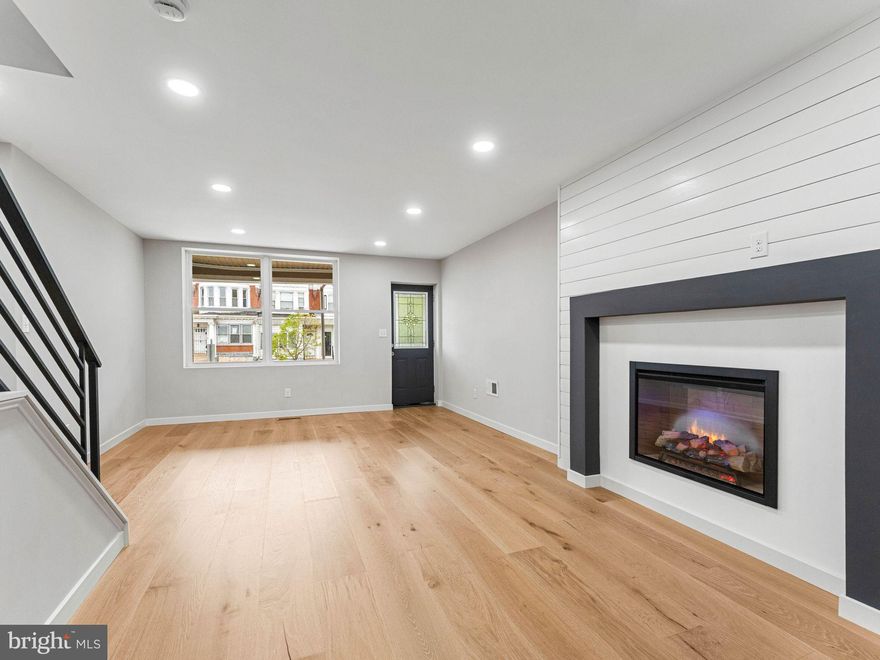 Discover the ultimate in modern urban living at 6058 Webster St, located in the heart of Philadelphia’s vibrant Cobbs Creek neighborhood. This 4-bedroom, 2.5-bathroom home has been transformed through a complete renovation, offering a sophisticated lifestyle just minutes from the scenic trails of Cobbs Creek Park and the convenience of University City. The main level boasts an expansive open floor plan that creates an immediate sense of scale. Warm new hardwood flooring leads you through the living space to a dramatic shiplap-featured electric fireplace wall, perfect for both quiet evenings and hosting guests.
The chef-inspired kitchen is a standout featuring, Black soft-close shaker cabinetry with sleek chrome hardware, Elegant white granite countertops and a sizeable breakfast bar along with stainless steel appliances.  Retreat to the second floor, where the primary suite serves as a true private haven. Highlights include soaring vaulted ceilings, a designer accent wall, and a luxurious modern primary bath. Three additional bright bedrooms and a contemporary hall bath provide flexible space for family, guests, or a professional home office. Enjoy even more living space in the large finished basement, which features durable laminate flooring and a convenient powder room—ideal for a media room or home gym. This home offers great outdoor space as you relax on the front patio and enjoy the neighborhood vibe or host private gatherings in the fenced-in back yard. Located in a walkable community with easy access to SEPTA transit, local shopping centers, and green space, 6058 Webster St is more than just a house—it's your New Home ...Schedule your private tour today!