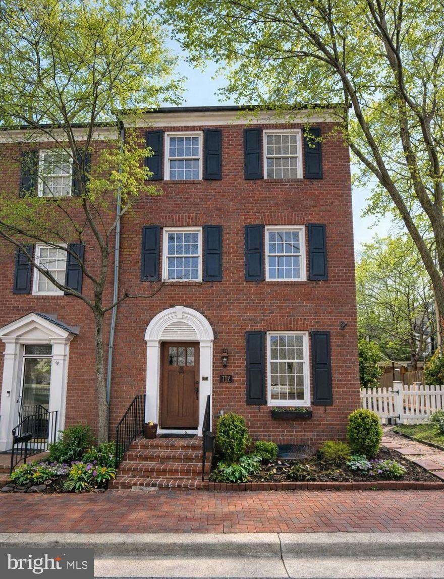 There are addresses in Kentlands that people know — and then there is 112 Kent Square Road. Tucked along the Kentlands Green, steps from the iconic Kentlands Mansion and Arts Barn, this dramatic, sun-drenched end-unit brick townhouse has been owned and lovingly transformed by the same family for over twenty years. And now, for the first time in two decades, it is available — and it is stunning.
From top to bottom, this home has been meticulously renovated — freshly painted throughout, with newly refinished Mahogany hardwood floors, a 2026 kitchen renovation featuring quartz countertops, Bosch stainless steel appliances, and a KitchenAid double oven. The family room anchors the main level, complete with a wood-burning fireplace. Every bathroom has been fully renovated — including a spectacular primary suite, where a double vanity, tub, and walk-in glass shower make every morning feel like a retreat, with sweeping treetop views and natural light pouring in to start the day. Custom Cherry wood doors open to dual closets with ample space and custom organization, plus a separate walk-in closet. A beautifully crafted Cedar banistered staircase connects the levels, leading to four bedrooms, a flexible den with windows and glass French doors — easily a fifth bedroom, home office, or guest room — and four and a half baths. Anderson full tear-out windows, fully functioning Cedar shutters, a 30-year Cedar Shake roof (2013), premium Nichiha Sierra siding, and a freshly updated Cedar picket fence complete the exterior.
There is a private flagstone patio beneath the shade of a grand Cherry tree — adorned with a charming fountain — made for dining al fresco under the lights on a warm summer evening. The side patio, overlooking the canopy of mature trees and the Kentlands Green, is a perfect perch for morning coffee, bird watching, and watching the neighborhood come to life. A detached garage and private driveway round out this exceptional home.
The lower level has been given equal attention: a brand new full bathroom, 2024 washer and dryer, new crown molding throughout, and two separate fully finished spaces that offer endless flexibility — a media room, a guest suite, a home gym, a playroom.
The community pool, the walking paths, the lakes, events at the mansion and theater and art classes at the Arts Barn, the farmers market, the boutique shops and acclaimed restaurants of Kentlands Town Square are all within effortless reach. This is Kentlands living at its finest.