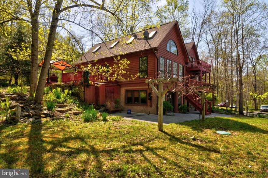 Paradise Found nestled perfectly atop a hill with gorgeous views of the morning sunrise overlooking Babb's Run on your thirty one acre, rolling landscape.  Located ten miles northwest of Winchester, Virginia and approximately seventy miles northwest of Washington, DC.  This one of a kind home and property is that of a dream come true.        This stunning well maintained Contemporary is ideal for someone looking for their own country  home with no HOA nor restrictions.  Truly an amazing parcel that offers lots of room for outdoor entertaining and bonfires while reveling  in the surrounding woodland     Five of the exterior doors are hand-crafted in solid mahogany.  The library also has the feature of three hand crafted mahogany pocket doors which will either close the room for privacy or allow it to open to the foyer.   All solid oak flooring and trim is custom made from a Mennonite planing  mill.  All trim is a full one inch thick and four inches wide with a custom designed profile.  The cabinetry in the library is solid cherry.   The spacious home's centerpiece is a large greenroom with a cathedral ceiling.  A quiet loft rests above the kitchen area.  The kitchen's entire cabinetry is solid cherry and custom made.  The library, master bedroom and third floor greatroom opens onto a deck overlooking a serpentine creek called Babb's Run.  The home was designed to view the creek from as many points as possible.     A new roof was installed in 2020 and a new heat pump installed in 2018 with a six year full parts and labor warranty remaining.  The home maintains a security system, plumbed for a  central vacuum system, garbage compactor  and backup propane heating for any unforeseen power outages.  There are heating elements embedded in the concrete  parking area for snow and ice melt.  A unique feature of the home is a walkout basement which has an indoor swimming pool measuring 8' X 14' with resistant jets for in-place swimming.  A private entry apartment has been built in this area by applying flooring over the area of the pool.  There is a floor placed over the pool which  can be removed and the pool returned to it's original function.  The basement area has a full kitchen, wine cellar, living room full bath and bedroom.    The third floor is also a greatroom or can be used as a  large bedroom,  with a fully tiled bath with skylight, and kitchenette.  It is an Ideal space for an office  featuring four skylights.  This area has it's own balcony which overlooks the creek.   The two car garage is on the same level as the walkout basement.   For anyone looking for solitude, peace, woodland,  a paw paw patch, wild edible and  medicinal plants, an open pasture, an old fashioned swimming hole,  and a home that bares artisan craftsmanship, then this is the home for you.  This home is also suitable as a corporate retreat.   The Thirty One Acres  has the potential to be subdivided into five (5 acre)  residential lots.    There are three separate wells on the property and one additional septic.  

***High end furniture, fine art and stained glass art will be an optional conveyance with negotiation on pricing.
Bridge does flood certain times of the year depending on extreme precipitation