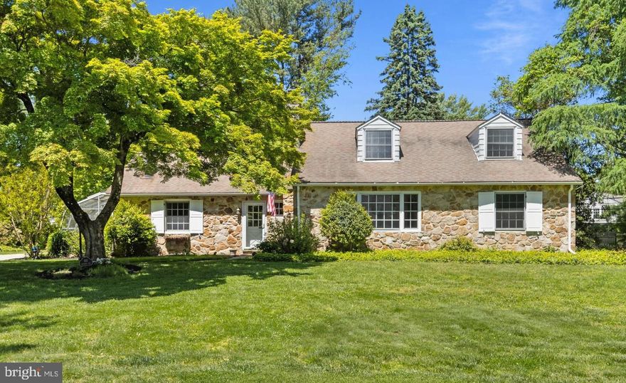 Nestled on a scenic and private property in a sought-after Radnor Township neighborhood, this charming 3-4 Bedroom, 2 Full and 1 Half Bath stone Cape Cod offers a rare opportunity to renovate and personalize a home surrounded by many higher-priced properties. Ideally located just a short stroll from Villanova University, Clem Macrone Park, restaurants, and train stations, the setting combines convenience with timeless neighborhood appeal. The Entrance Hall welcomes you with a convenient coat closet and Powder Room and opens to both the spacious Living Room and inviting Family Room. The large Living Room features a classic wood-burning fireplace, a picture window with a deep windowsill, and abundant natural light. The sunny Dining Room showcases elegant wainscoting and flows seamlessly into the dramatic vaulted Family Room, complete with a wall of built-in shelving and cabinetry, plus a wet bar perfectly positioned for entertaining. Random width, pegged hardwood floors add classic charm to most of the main floor rooms. Glass doors from the Family Room lead to the greenhouse, which also leads towards the detached 2-car Garage—making this an ideal space for a future Mudroom, Office, or creative flex area. The Kitchen is equipped with a stainless Bosch dishwasher, stainless GE French-door refrigerator with freezer drawer and icemaker, and a newer GE smooth-surface electric range. A door from the Kitchen opens directly to the rear stone patio for easy indoor-outdoor living. The main level includes a desirable Primary Bedroom suite with a closet and adjoining room ideal for an Office, Dressing Room, or Nursery.  This room was formerly the 4th Bedroom, and could be used to create an en suite Primary Bathroom. Nearby, a Full Hall Bathroom features a newer white shower enclosure. (This space could be used to expand the Kitchen.) Upstairs are two additional Bedrooms with closets and a Hall Bathroom with double vanity. The walk-in attic, off Bedroom 2, offers potential for future expansion. The partially finished Basement adds valuable living and storage space with a large Rec Room featuring Bilco doors to the rear yard, plus a separate Laundry Room, Workshop, Storage Room, and Utility/Mechanicals Room.  Surrounded by flowering shrubs and specimen plantings, you’ll enjoy a peaceful retreat in one of Bryn Mawr’s most desirable locations. Convenient access highly-ranked Radnor Township schools, the Blue Route, Center City, Airport, and corporate/medical centers. This is an exceptional opportunity to bring your vision to life in a coveted Main Line neighborhood.