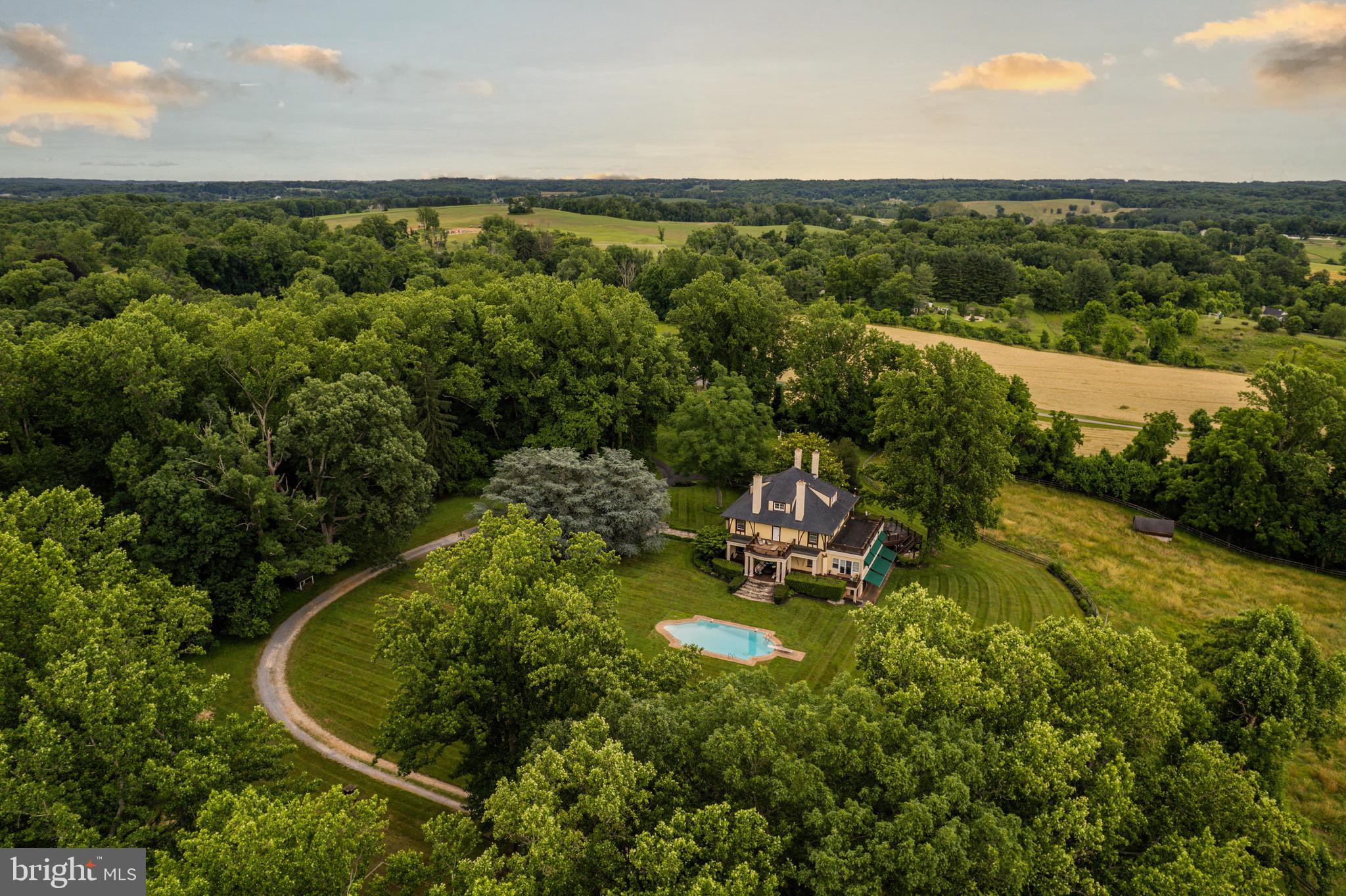 Live authentically. The Oread—a masterwork of architectural distinction, steeped in history and timeless elegance. This circa 1904 estate, once the visionary home of Henry Perky, inventor of shredded wheat, embodies a harmonious fusion of enduring period craftsmanship and bold, sophisticated reinvention.
At its heart, a dramatic staircase ascends within an octagonal living hall, a breathtaking centerpiece that anchors the home’s architectural splendor. Expansive verandas and porches extend the living space, inviting both grand entertaining and serene reflection. The estate unfolds with luxurious amenities: a classic pool, tennis court, and a collector’s car barn. A guest house offers refined hospitality, while a 40' x 15' gourmet kitchen—appointed with European fixtures—is a stage for culinary artistry. The glamorous owner’s suite is a private sanctuary of elegance and repose. A third-floor destination multi-room guest suite crowns the estate, offering soaring ceilings, breathtaking panoramic views, and a sense of retreat high above the landscape—an exquisite haven. Beneath the estate, an underground stone-and-plaster tunnel leads to a magnificent wine cellar, a hidden retreat where conversations linger into the night by invitation. The property’s private speakeasy, seamlessly connected to a gracious dining room, sets the scene for intimate gatherings and spirited celebrations. Set upon 19.27 acres of rolling landscape, this estate welcomes your horses, visions, and aspirations. Heirloom apple trees, unfettered privacy, and breathtaking panoramas create an atmosphere of unparalleled tranquility. A rare and soulful property, The Oread is more than an estate—it is a legacy, an experience, and an extraordinary opportunity to script the next chapter of your life. The Oread has 2 heated and cooled buildings that house up to 12 cars. Proximate to the NCR and The Milton Inn. Internet access - Comcast Dedicated Fiber. Cultivate your existence. The art of uniting human and home.