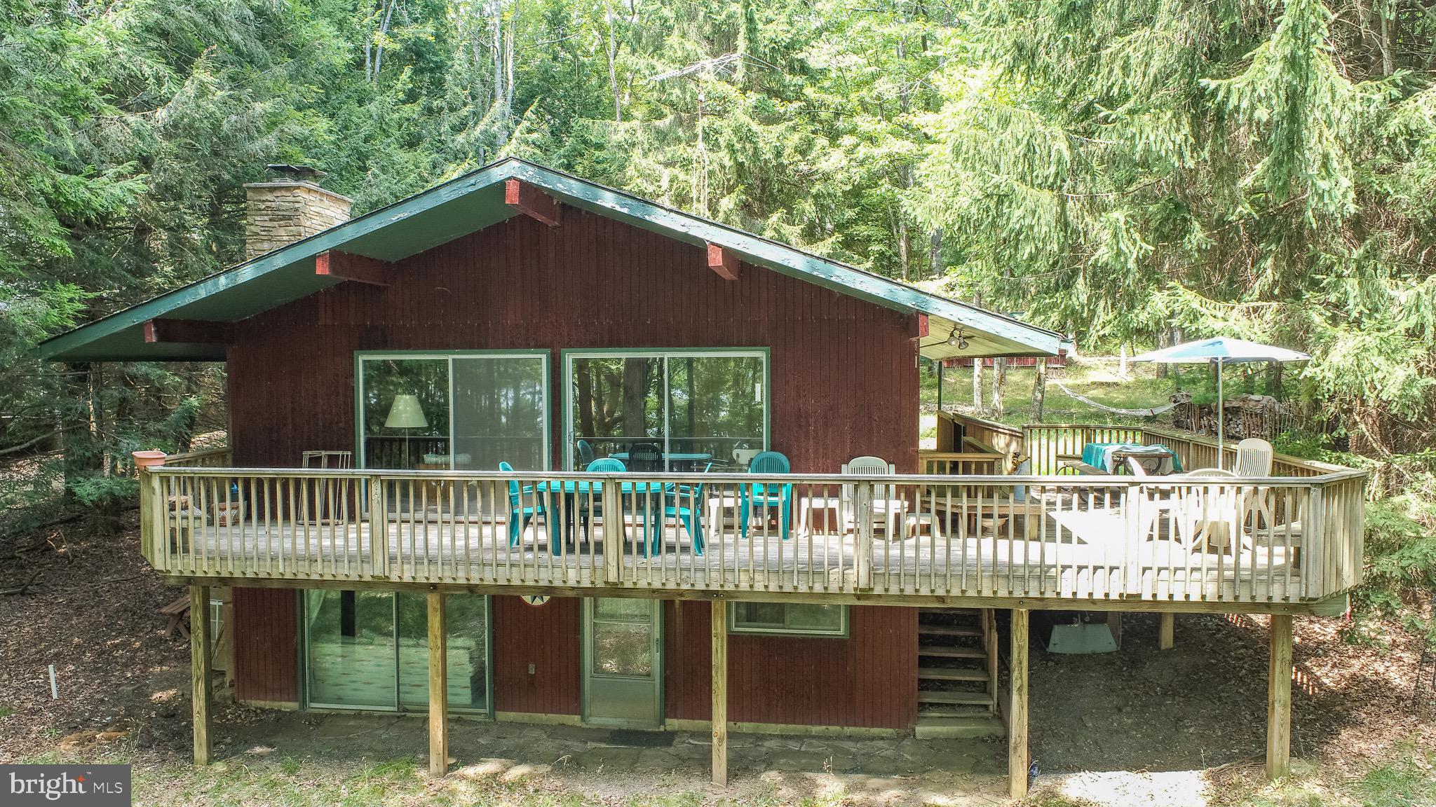 This rare lakefront opportunity on the quiet south end of Deep Creek Lake features one of the best waterfront lots on Shoreline Drive—gently sloping, beautifully situated, and ideal for future building.
The property spans both sides of Shoreline Drive, providing extra space, privacy, and potential for septic expansion or additional structures. With mature trees, flowering shrubs, and a peaceful setting on a no-through-traffic road, the lot offers a serene retreat in one of the lake’s most desirable neighborhoods.
Located just minutes from the new Thousand Acres Golf Club, this property also offers convenient access to hiking and cross-country trails, plus year-round outdoor activities. Shoreline Drive is known for its quiet, private atmosphere and scenic beauty—an ideal setting for those seeking a calm, nature-oriented lifestyle.
While the existing home is modest and largely original, it includes wood floors, cherry paneling, a wood stove, and a finished basement. A circular driveway offers ample parking, including electric hookups originally used for an RV. Additional structures include a newer boat shed and a garage suitable for small boat or car storage. This is an excellent opportunity to invest in a premium lakefront location with endless potential for transformation.
