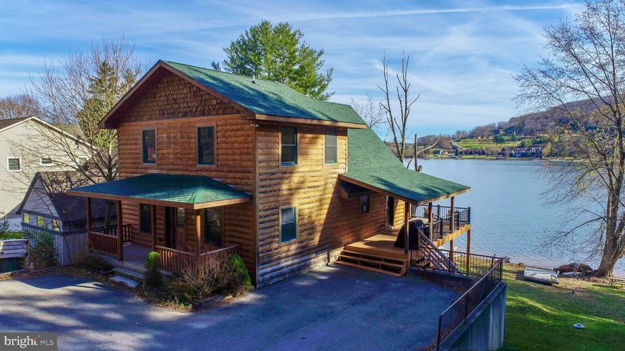 You can have the best of both worlds with this lakefront log home! The lake is steps away, and just a few houses away from Main Street Ski slope at Wisp.  If you're looking for an income producing property, the last 3 years the numbers are consistently from $86,000 to $90,000 a year. The home has soaring cathedral ceilings with stunning views of Deep Creek Lake.  Spacious open living, kitchen, dining for all your family entertaining. The kitchen has an island to gather for meal prep and plenty of cabinet space.  A cozy stone fireplace for those after ski evenings!  The main level primary bedroom is private with an adjoining bath.  For those who can work remotely there is a room off of the entry that is perfect for a home office.  A half bath completes the main level.  The upper level has two spacious bedrooms with a large bath between.  Movie nights for all in the spacious lower level with a wet bar and a second stone fireplace.   There is also a large bedroom and bath with a tiled shower.   The home is just steps away from the kind lakefront everyone is looking for.  There is a hot tub overlooking the lake and a wonderful hardscaped fire pit for smores and stories!  Wisp Ski Area is just a few houses down the road. Minutes from the tubing park, ASCI Whitewater Course, Lodestone and Wisp golf course!  If you are looking for an affordable lakefront home, that is also an income producing property, look no further.  When they say LOCATION, LOCATION LOCATION, this is what they are talking about!