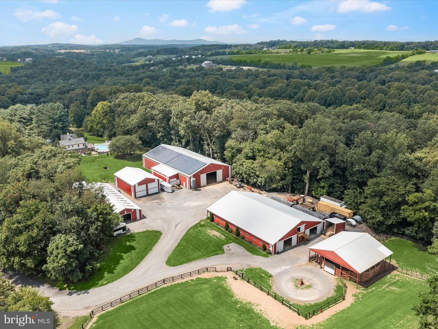 Set on 25 picturesque acres with a meandering creek, this world-class equestrian estate offers an unparalleled blend of professional horse facilities and refined country living—all within an easy drive of Washington D.C., Baltimore, and Northern Virginia. Designed with precision, care, and comfort in mind, the property is turnkey for the serious equestrian, trainer, or discerning private owner.  At the heart of the farm are two exceptional barns, totaling 45 stalls, thoughtfully designed for safety, convenience, and efficiency. The main barn boasts 29 matted stalls across two wide 12-foot aisles, each equipped with its own fan, light, and timed outlet. Amenities include a climate-controlled lounge, two spacious tack rooms, a wash stall, an insulated laundry room, a utility room, and a massive loft with guest accommodations. Dedicated farrier lighting and ample tractor clearance make daily operations effortless. Just steps away are an indoor arena, a large shavings shed, an additional 7 stalls, and a hay storage container that keeps dust to a minimum.  The second barn offers 9 matted stalls, a charming guest room, a full bath, and a two-bedroom suite ideal for visiting riders or staff. A vehicle lift in the barn provides space for on-site equipment maintenance.  For the rider, the property features a large 60x120' indoor arena with sand footing and lighting, powered by a leased solar panel array with five inverters in the attached workshop. Outdoor training spaces include a 175’ x 275’ arena with new footing, a 48-foot covered round pen, and a 4-horse ProWalk hot walker. Pastures are immaculately maintained, enclosed by safe wood fencing, and laid out for ease of rotation and turnout.  Additional accommodations include a caretaker’s cottage and barn apartment, both updated for comfort and practicality.  The four-bedroom main residence blends casual elegance with warmth, featuring hardwood floors, two gas fireplaces, a great room with brick-surround fireplace, cathedral ceilings,  and skylights, a formal dining room with built-ins, crown molding,  and designer lighting, and a main-level primary suite with the flexibility to expand. The updated kitchen with island and stainless steel appliances, granite counters,  opens to light-filled living spaces, and the unfinished basement with rough-in offers room to grow. The upper level provides three spacious bedrooms, one with an en-suite bath with a soaking jetted tub, a walk-in shower, and a walk-in closet.   Outdoor living is elevated by a newly remodeled heated inground pool with fountains, new tile and plaster, a sun deck, and a covered patio surrounded by lush perennial gardens.  Additional amenities include a Two-car attached garage with EV charger, an RV garage with 16-foot ceilings, 14-foot doors, and 100-amp service, designed for Class A RVs, large living quarter horse trailers, or future conversion to a gym, basketball court, breeding facility, or stallion station.  Every detail of this estate, from the safe fencing to the solar power, from the manicured arenas to the luxurious living quarters, has been crafted for the ease of care and enjoyment of horse and rider alike. With proximity to top equine veterinary hospitals and premier showgrounds, this is a rare opportunity to own one of Montgomery County’s finest equestrian properties. Shown by private appointment only.