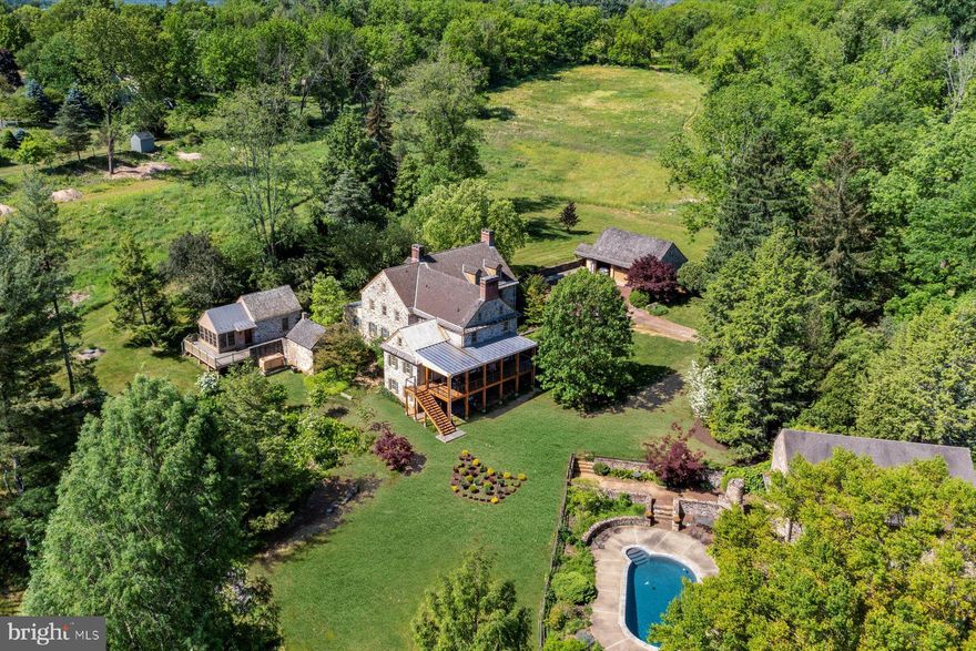 ** Fabulous opportunity & priced to sell. Now offered with 59 + acres. ** Cradled at the end of a long country lane is “One of Bucks County’s most meticulously preserved & restored stone houses”. Resting on a portion of an original land grant given by William Penn to George Pownall in the late 1600’s & settled by his son George Jr. & his wife Hanna circa 1710. With respect for the past & vision for the future, great thought & attention to detail have been dovetailed elevating a late 18th century home with its 21st century equal. Meticulous restoration & authenticity can be savored in this refined country estate. Balance & symmetry are seen in stunning pointed stonework, beaded siding, wood shake & metal seam roofs balanced by stately proportioned brick chimneys & period doors, lighting fixtures & hardware. Well planned landscaping, ornamental trees & shrubbery grace the property. Massive hewn stone steps, intricately stacked walls & walkways add to its appeal. Upon entering this remarkable home, you immediately sense a fascination to further explore, “a home like no other”. Lustrous pine floors & fine hardware add grace & charm to each of its rooms with an eye of savoring expectation. The formal living & sitting room w/ fireplaces have paneled cabinetry & bookshelves. Large D/R provides a special place for family gatherings.  The tavern room keeps company with a perfectly proportioned fireplace & offers wet bar w/ fridge & wine cooler. Large country kitchen w/ plentiful cabinetry, high end appliances, soapstone counters, center island & walk-in pantry will please any experienced cook.  The breakfast area is warmed by an impressive stone fireplace. Masterfully created great room with its inviting presence is the heart of the home. This wonderful space combines elements of its huge summer beam, exposed chamfered joists. It is complemented by a large mantle fireplace flanked by tall French doors that open to a marvelous, covered porch capturing pleasant views of woods & field. An adjacent media room enjoys similar rare architectural elements. Six fireplaces add to the ambience on those winter evenings! The luxurious main bedroom suite w/ sitting area & lavishly appointed limestone bath includes a double marble vanity, whirlpool tub, oversized shower w/ tumbled marble accents + 3 walk-in closets. 3 bedrooms, with their own character, a laundry room and an add’l bath are located on this level. The 3rd floor offers a substantial suite w/ cathedral ceiling & exposed post & beams. A full custom bath includes pedestal sink, soaking tub & separate shower.  Add’l rooms at this level include sitting room + flex space room w/ striking exposed stone wall.  The finished walk-out lower-level w/ radiant heated floor adds versatile space + kitchenette w/ micro-wave, dishwasher & Sub-Zero refrigerator & custom full bath w/tumbled marble shower details complete this space. A great spot to enjoy billiards, games, hobbies or just to chill! French doors open to a stone patio with easy access to the pool.  A delightful 2 room guest cottage of consistent quality has wraparound private deck. Featuring kitchenette & full bath, random pine floors, cathedral ceilings, exposed beams. Spring house w/ garden storage adds to the charm. Sweeping lawn surrounds the home & leads you to a fabulous, heated, saltwater in-ground pool w/ separate spa. Stunning elements can be appreciated in the intricately designed ornamental ironwork fencing & gate.  A sitting area between the stone bank barn & pool adds that perfect spot for outdoor entertaining. Across the courtyard driveway is a 3-car detached garage. Improvements by the current steward of this breathtaking home include new septic system, covered porch of superb craftsmanship & many finely enhanced items, too numerous to mention. Mechanicals are impressive w/ custom concealed Lutron lighting, zoned geothermal HVAC, radiant heat, on demand hot water & whole house generator.