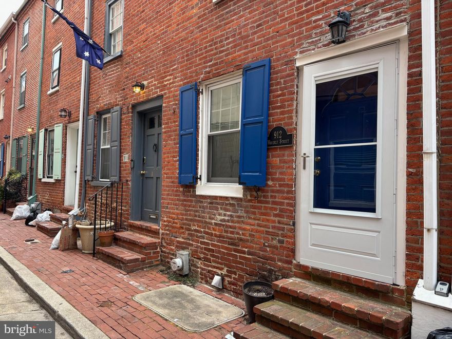 Location, location!! This adorable, meticulously-maintained brick-front trinity is tucked away on a historic lane in the Washington Square West neighborhood. The block is so quiet, you’ll forget you’re in the city at all, yet you’re right around the corner from everything essential. The living room is large with recessed lighting and classic wainscoting, along with a coat closet and wood plantation shutters for privacy. The back door leads out to a wooden bridge that accesses the gated, shared courtyard. Below, the kitchen has everything you need including decent counter and cabinet space, stainless appliances, pantry, extra shelving and dining area (table included); the sliding door leads out to an enclosed patio. The second floor has full bath with full-size tub; the bedroom on this floor is ample size and features two closets as well as floating shelves. The sunny 3rd floor is a large bedroom with 1/2 bath, vaulted ceiling and fan, sliding-door closet and additional overhead storage spaces. There is a South-facing balcony with retractable awning, overlooking the gated courtyard. Notable features include original wood floors and recessed lighting throughout the house, central AC, and 3 outdoor spaces. Washer and dryer in kitchen. Around the corner from South Street Whole Foods and Acme, the Italian Market, and plenty of dining and shopping options. Extremely close to Jefferson and Pennsylvania Hospitals, Washington Square, Center City...pretty much everything! Pets considered. Available April 1.