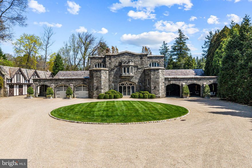 A stunning showcase of Tudor Revival architecture, 56 Crosby Brown Road is a set on 2.8 level acres on a private lane in the heart of Gladwyne on Philadelphia’s prestigious Main Line. Built between 1895–1905, this gorgeous, one-of-a-kind estate seamlessly blends historic grandeur with modern luxury. This exceptional property has been meticulously updated to provide every modern comfort with details executed to perfection.
A dramatic entry Loggia leads you to grand leaded glass doors where you enter the foyer and center hall anchored by limestone with granite insets and custom limestone surrounds. Crowned by a soaring 25-foot beamed ceiling, the formal living room features a marble wood-burning fireplace with rich millwork and cabinetry, an impressive space for gatherings with access to one of three terraces that look out over the gardens. With its striking hand-crafted leaded glass window, the formal dining room is ideal for seamless entertaining, featuring a concealed doorway providing direct access to the butler’s pantry, wet bar and wine room. The main level also features an exquisite paneled library bathed in natural light from floor-to-ceiling sliders that lead you to the center terrace and gardens. 
Designed with exquisite custom artisan cabinetry by Downsview Kitchens and featuring Hereau fixtures, Miele appliances and Wolf ranges, this expansive kitchen flows effortlessly into the family room creating a warm and functional space for everyday living. Centered around a grand limestone gas fireplace, the family room offers a comfortable gathering place with direct access to the patio, outdoor kitchen and rear gardens. Adjacent to the kitchen, a spacious sun-drenched bonus room that formerly housed a lap pool with the potential to be restored, now serves as a bright gym and relaxed lounge area. Completing the main level is a laundry room, formal and informal powder rooms, and full bath.
Ascend to the second floor, where dramatic 25-foot ceilings boast beams inlaid with hand painted canvases.The primary suite has vaulted ceilings, rich wood paneling with built-in closets, a sitting area, and an exquisite, extensively renovated ensuite bath featuring an Italian marble throughout and Sherele Wagner Fixtures. The second floor also features three sizable en-suite bedrooms, all benefiting from modern comforts and newly renovated bathrooms. One of these includes a welcoming gas fireplace.
Next to the main home is a charming, completely renovated 2-bedroom, 1-bath carriage house with a full service kitchen. The half-timbered exterior recalls an English country home, while modern amenities provide today’s desired comforts. It can be used as a guest house or home office.
A circular driveway with  attached garage; original stone potting shed, extensive stone terraces with outdoor kitchen; and meticulously landscaped yard and gardens that were once an arboretum complete this serene retreat.
This historic gem is located in the prestigious Lower Merion School District just 1.7 miles from the Haverford and Ardmore train stations, with service to Phila. and NYC.  2 miles from Merion Cricket Club, 10 miles to center city Phila., close to various private schools, restaurants and shopping. With its unparalleled combination of history, craftsmanship, and modern elegance, 56 Crosby Brown Road is truly a Main Line legacy property.