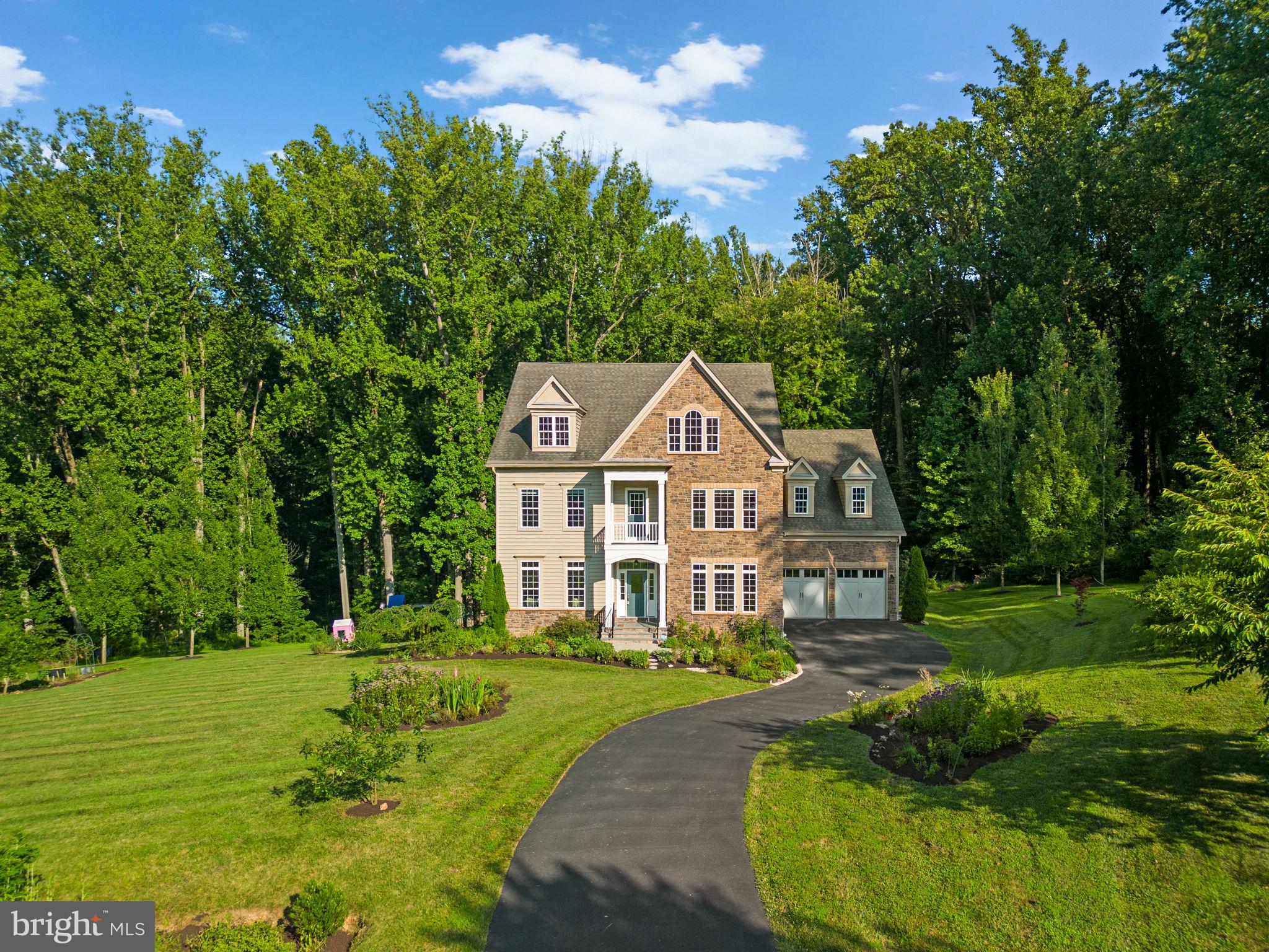 Nestled on a secluded 1.1-acre lot in the highly sought-after Spring Valley Estates, this elegant Colonial, built in 2017, offers refined living surrounded by lush landscaping and mature trees. A long, private driveway welcomes you home to this serene retreat.
Step inside to beautifully maintained hardwood floors that span the main level, where bright, open-concept living spaces are enhanced by custom window shutters and thoughtful design details. The foyer gracefully opens to both the formal living room and the dining room, highlighted by timeless architectural accents, including chair rail molding and a statement chandelier. A well-appointed butler’s pantry leads to the gourmet eat-in kitchen, featuring 42” cabinetry, stainless steel appliances, a chic white subway tile backsplash, and luxurious granite countertops. A large center island with bar seating glows under two sparkling chandeliers, while the sun-drenched breakfast room offers access to the composite deck and a spacious mudroom with built-in storage. Open to the kitchen is the inviting family room, the true heart of the home, centered around a cozy gas fireplace, perfect for everyday living and entertaining. Completing the main level are a sophisticated home office, ideal for remote work or quiet study, and a beautifully appointed powder room.
Upstairs, plush carpeting spans the four generously sized bedrooms and three full bathrooms. The centrally located laundry room adds ease to daily routines, while a loft with hardwood flooring and access to a charming front balcony offers flexible living space. The luxurious primary suite is a true sanctuary, featuring a tray ceiling with an elegant chandelier, an expansive sitting room, a massive walk-in closet, and a spa-inspired en-suite bath. Enjoy the oversized glass-enclosed shower, dual vanities, and a large soaking tub—ideal for unwinding at the end of the day. One of the secondary bathrooms features dual access and double sinks, shared by two bedrooms, while the fourth bedroom boasts its own private en-suite and walk-in closet. The fully finished, walk-out lower level features a spacious recreation room with custom built-ins and a full bathroom (renovated in 2021), perfect for entertaining and relaxing. Additional storage space is also available.
Outdoor living is just as impressive, with a low-maintenance composite deck, a covered patio below, a storage shed, garden beds, and a sprawling, beautifully landscaped backyard that backs to serene woods and a charming creek, offering unmatched privacy and natural beauty.
