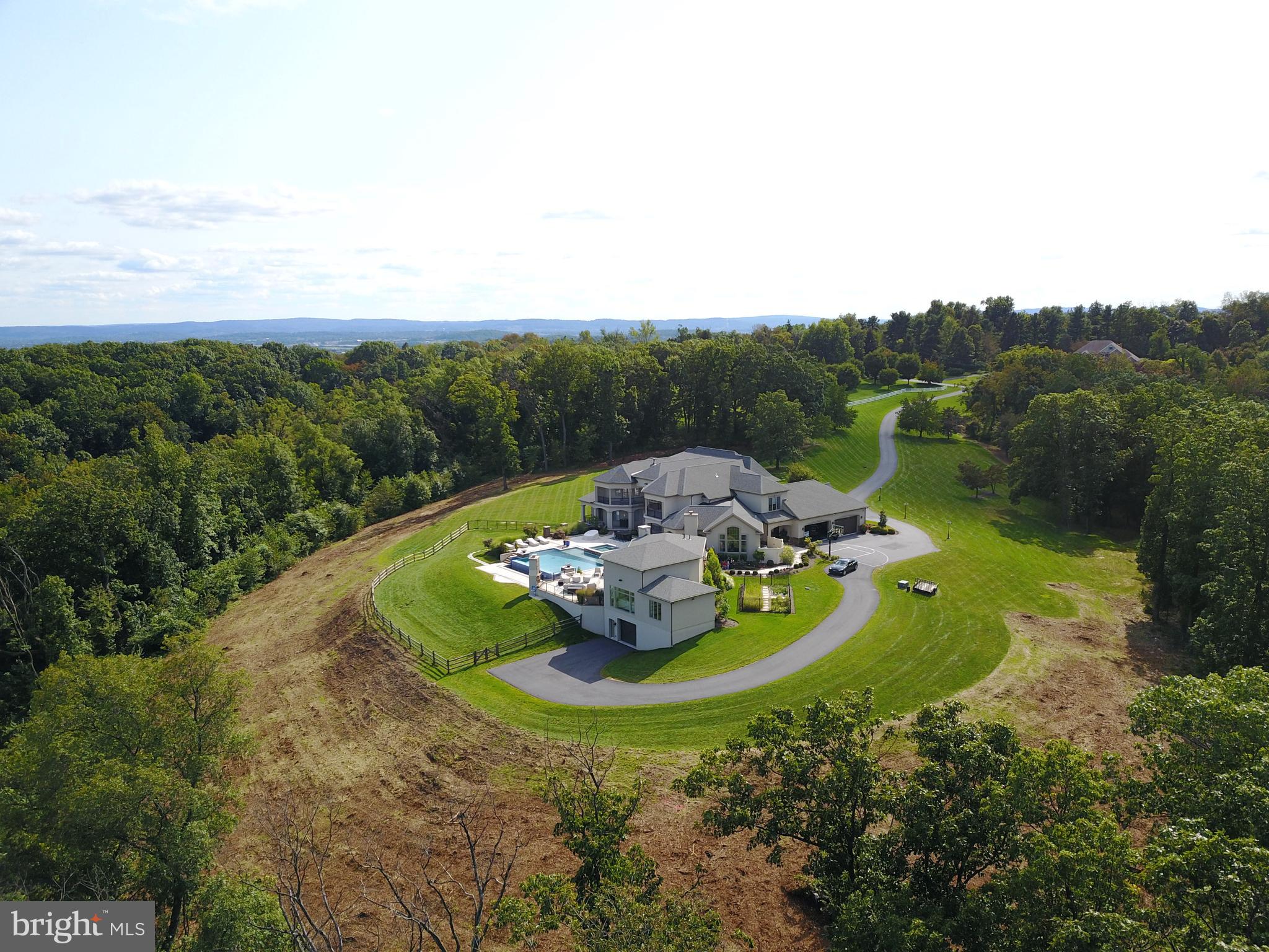 Once in a lifetime opportunity to own this absolutely stunning 26.61 acre estate with over 9,000 sq. ft. of living space. Gorgeous 2-Story with 6 bedrooms, 6 ½ baths, heated, in-ground infinity pool/hot tub and pool/guest house all awaiting your arrival. The circular driveway leads you to the double front door and into the 2 story foyer with amazing marble flooring, columns, chairrail, crown molding, motorized chandilier and a grand curved staircase to the upper level. The formal dining room is adorned with a crystal chandeliers, tray ceiling, wainscoting and crown and beautiful hardwood. The 2-story great room hosts a coffered ceiling, an amazing floor to ceiling stone gas fireplace with built-ins and lighting, rear staircase and a wonderful wall of windows warms the entire room. A chef’s kitchen comes with all the appliances you will ever need, including a double wall oven, Miele instant coffee maker, Viking gas range with pot filler, Viking refrigerator, an incredible island with wine cooler and vegetable sink, coffered ceiling with recessed lighting, granite countertops, marble flooring and peninsula seating. There is also a wet bar right around the corner with another cooler. The breakfast area has a tray ceiling, marble flooring and two access points to the rear of the home, overlooking the pool and landscape. The formal living room has hardwood flooring, beamed cathedral ceiling, gas fireplace with built-ins and access to the covered rear, heated patio with a fireplace, recessed lighting and tv hook up. Luxurious first floor primary bedroom with wood floors, gas stone fireplace, crown molding and tray ceiling and a large sitting area with access to the rear patio, overlooking the pool. The primary en suite has a soaking tub, double vanity, private storage closet and a marble surround shower with dual heads. There is also a primary walk-in closet, with two access points, and a large center island and ample storage space. The large, private main floor office has hardwood, crown molding, built-in cabinets and large closet, and could be used as a secondary main floor bedroom. The main floor hall has crown molding and cabinet storage and there is a main floor laundry room with marble flooring, drying rack, sink and built-in storage, a large mud room with built-in storage/seating and a powder room. The upper level consists of three ensuite bedrooms, all with either walk-in closets or large closets, crown molding and tray ceilings, as well as two additional bedrooms that share a jack-n-jill bath and three bedrooms have access to private balconies. The daylight, walk-out lower level of this estate is ready to be finished off for even more living space. The pool/guest house is absolutely amazing and comes with an open concept floor plan which allows for a great entertaining space, 2-story with bead board ceiling and lovely board and battan accent wall, a fabulous kitchen with granite countertops, range and built-in grill, wine cooler, dishwasher and indoor/outdoor seating from the pool patio, which is also heated. There is a dining area and large bedroom with 2 closets, as well as a full bath with an amazing tile surround shower. Additional amenities included a heated 4-car garage, separate 2-car garage, whole house speaker system, including the outdoors and a security system. Easy access to Routes 183 and 61. You have got to see this one for yourself!