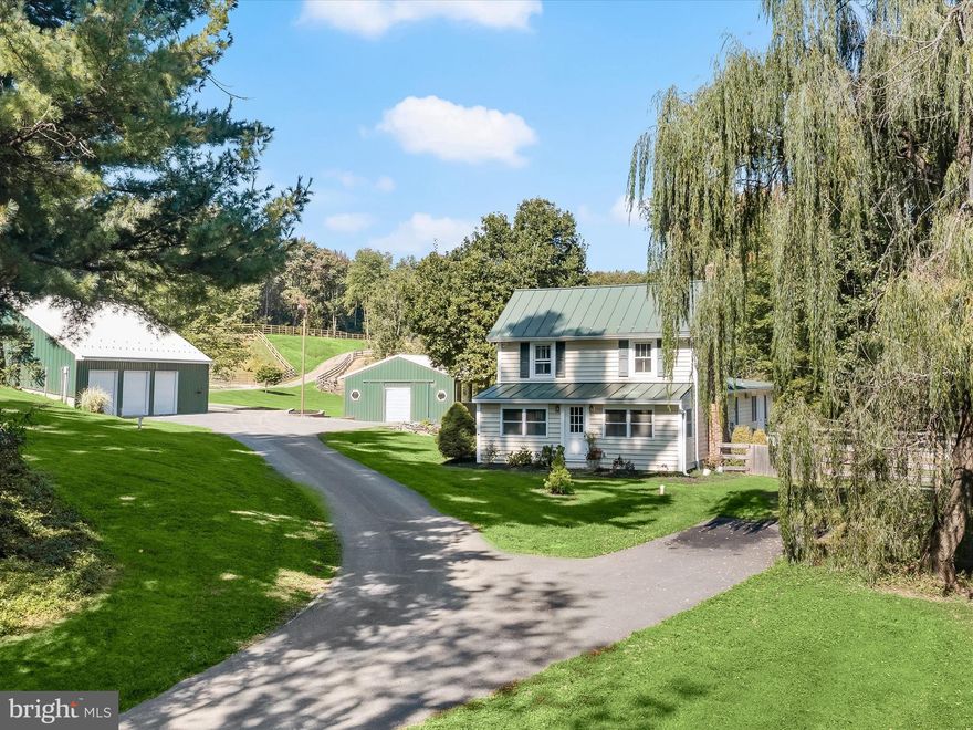 As you arrive at this enchanting 21-acre horse farm in Carroll County, an electric gate welcomes you into a property that feels like a storybook setting. To your right, a sparkling pond with an electric fountain sets the tone for the sense of wonder that unfolds across rolling hills, conifer groves, and fruit trees. Every detail has been thoughtfully designed for both horses and people, creating a place that is at once practical, whimsical, and full of character.

The main house offers nearly 3,000 square feet above grade, with four bedrooms and two full baths. Its renovated kitchen delights with granite counters, stainless steel appliances including a gas range and hood, a farmhouse sink, soft-close cabinetry, and an island with breakfast bar seating. The kitchen flows seamlessly into the dining room, where a beamed ceiling and brick fireplace with insert add warmth and charm, mirrored by the front living room with its own beams and fireplace. An enclosed porch off the living room, surrounded by windows, invites you to sit and savor every season.

Beyond the kitchen and dining areas, a bonus room makes an ideal home office with backyard access, while a nearby laundry and mudroom keep daily life organized. Many original hardwood floors remain, balanced by updated Pergo flooring upstairs and in two bedrooms. The upper level reveals a spacious primary suite with a soaring cathedral ceiling, along with two additional bedrooms highlighted by exposed beams. A walkup attic has been foam insulated and floored, while the unfinished lower level with exterior walkup access offers versatile storage or hobby space.

The equestrian facilities are nothing short of exceptional. Five pastures are equipped with automatic waterers, professionally planned drainage, and gravel-framed gate entrances, ensuring both beauty and function. Multiple run-in sheds, including two high-end poly vinyl structures, provide shelter, while a tack shed, hay shed, and hitching post with bench add convenience and charm. A newly built outdoor arena, designed this year with Bluestone footing, dual French drains offers impeccable drainage and performance. Trails wind between pastures, inviting long rides beneath the sky, while graded land beside the arena is already prepared for your dream horse barn to be set in place. Every pasture and field on the property has been thoughtfully set up for boarding, ensuring convenience and comfort for horses and handlers alike.

Additional structures add to the property’s versatility. A detached office, fully insulated with its own HVAC and water, can serve as a professional workspace or creative studio. A machine shed provides extra storage for equipment, while the three-car garage includes a guest suite above, complete with a bedroom, bath, kitchen, and its own washer and dryer perfect for guests.

Every corner of this property tells a story, from the wildlife that meanders through the fields to the carefully placed gravel paths and fountains that reflect the owner’s vision of harmony and function. It is a place where horses thrive, friends gather, and nature seems to lean in close, offering a sense of wonder and sanctuary that is rarely found.