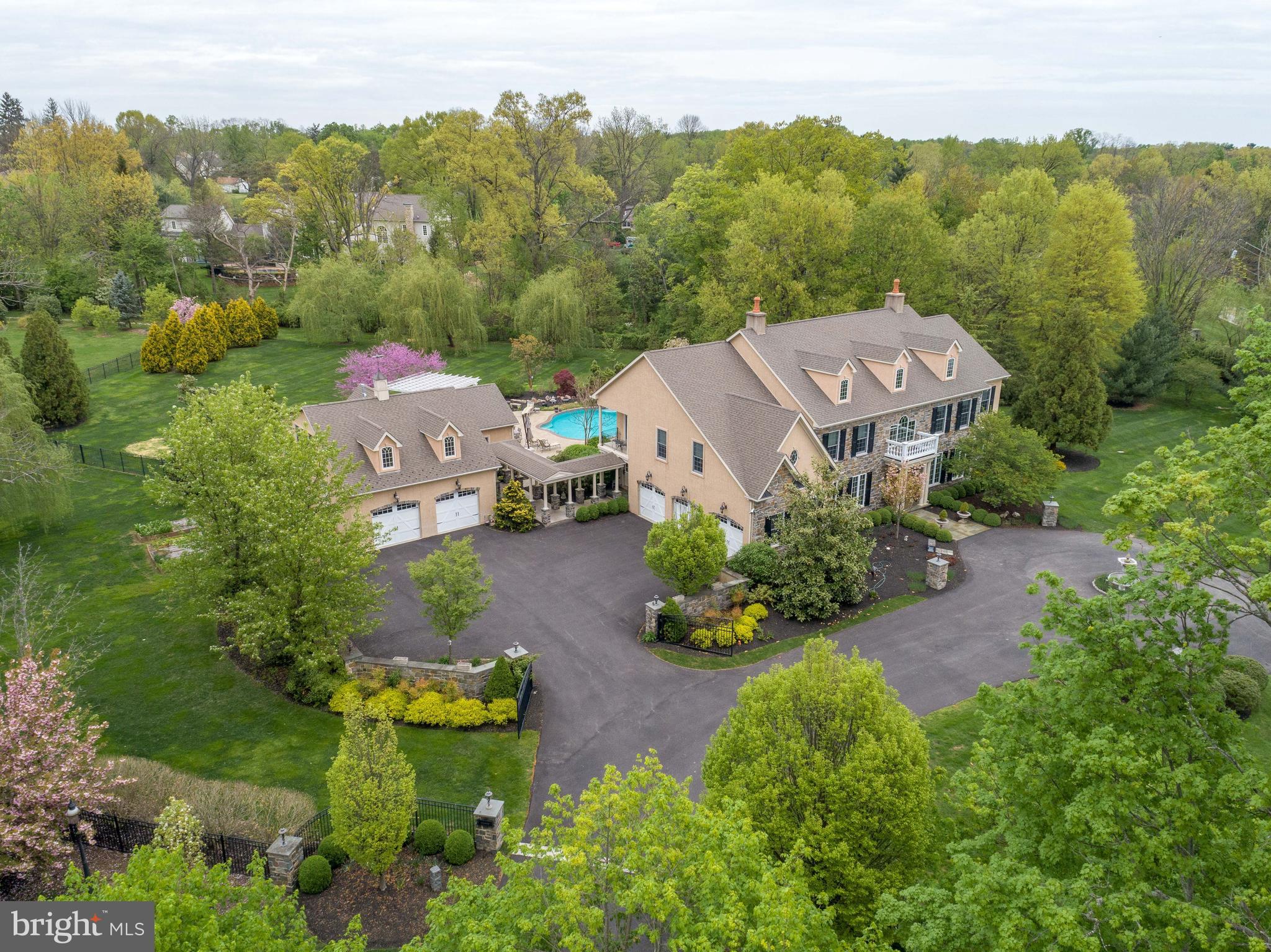 Custom designed rare gem offers an exclusive blend of warmth and exquisite amenities in over 9300 square feet of living space including the separate carriage house. A private lane leads to a beautiful driveway, large front circle and picturesque fountain framing the front exterior of the home, and a gated walled courtyard with five garage bays and a second gorgeous fountain. Enter the main home through the foyer with marble flooring, a two story cathedral ceiling illuminated by wrought iron chandelier, and a sweeping staircase. The foyer leads to the spectacular dining room with custom millwork, lots of natural light, and a living room with gas fireplace. The gourmet chef's kitchen with abundant sunlight includes a large granite island that seats 5, with double sink, disposal, microwave, warming drawer, and Bosch dishwasher. Behind the island is a granite countertop, and marble baking counter, a Viking six burner range with griddle and two ovens, plus an oversized vent hood. Two large Viking wall ovens, a Sub Zero refrigerator, and a separate Viking freezer, both floor to ceiling complete this area. The butler's pantry has more cabinets, with sink, a second Bosch dishwasher, and disposal. Finally there is large built in desk with shelving plus an amazing walk in pantry. Attached to the kitchen is a beautiful morning room with heated Mexican tile flooring and sliding doors on 3 sides leading to the pool patio. A mud room off of the kitchen has a half bath, cubbies, and stacked washer/dryer leading into a 3 bay garage and courtyard. The garage has a built in trash compactor and custom wall and flooring system. The incredible family room features cathedral ceilings, floor to ceiling picture windows and French doors overlooking the pool, English hand laid patio, and hammock area. Gorgeous built in cabinetry surrounds gas fireplace, and a back staircase and an indoor Juliette balcony. Finally a wet bar with custom cherry top, wine fridge, and a copper bar sink. On the second floor is the master suite with a vaulted ceiling, sitting area with fireplace, bookshelves, cabinetry, and a mini refrigerator. There are large his and hers closets and a separate dressing area with a marble top vanity and balcony overlooking the courtyard. A spa- like master bath has an oversized Jacuzzi tub, separate vanities with sinks, a multi-head glass enclosed shower and a separate water closet. There are three additional large bedrooms, each with walk in closets and bathrooms and a large laundry room. The third floor has a large guest suite plus full bath large sitting area and a spacious semi finished attic with built in shelving for storage. The basement, which has over 2000 finished square feet, contains a custom "Irish Pub" style bar with sink, dishwasher, bar refrigerator, cabinets and glass shelving. There is also a large gym, an arts and craft room ,a media room with a 100 inch projector screen and theater seating, a powder room, and a large utility/storage room. Extra wide walk up stairs leads to the pool patio welcoming abundant light. Behind the house is a "stay-cation" paradise featuring a large heated salt-water pool and separate spa, both with LED lighting, and separate heaters and pumps. There is an outdoor "Jersey Shore" style enclosed shower, an entertaining area with bar seating, a gas fireplace and a large built-in gas grill and ice cooler under a pergola. A second pergola is the hammock area under oak trees. The manicured lawns, flowerbeds and grounds feature extensive low voltage lighting. The carriage house completes the estate, which has a gorgeous breezeway connected to the main house and the pool patio. Included are 2 oversized garage bays with a custom wall and flooring system, and two storage sheds. First floor has a large living area, vaulted ceiling, kitchenette, changing area, stacked washer/dryer, and a half bath. Upstairs are two large finished rooms separated by pocket doors and a full bath.